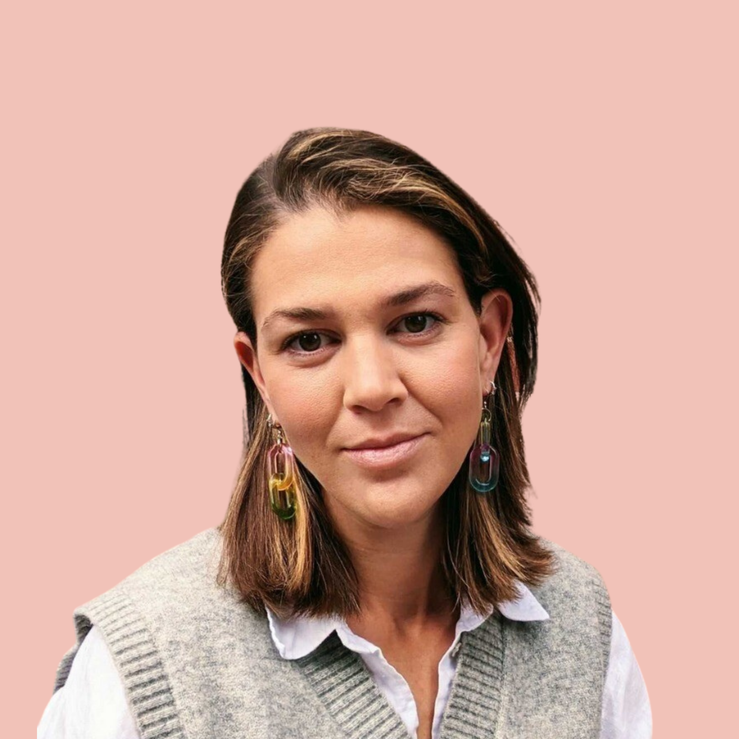 Lauren Lord with a pink background wearing a gray vest and colorful earrings