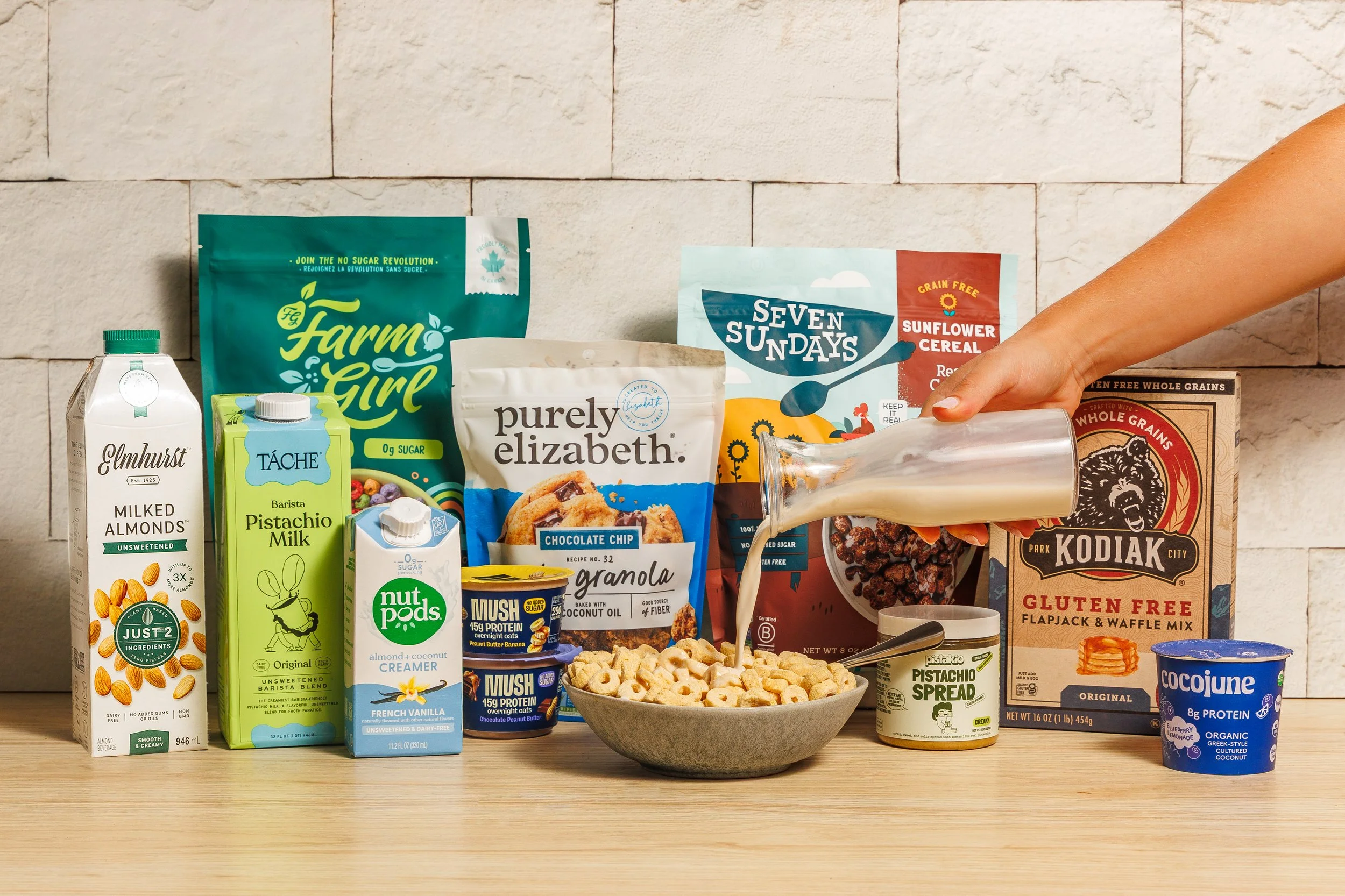 Assortment of packaged food and beverage products displayed around a bowl of cereal.