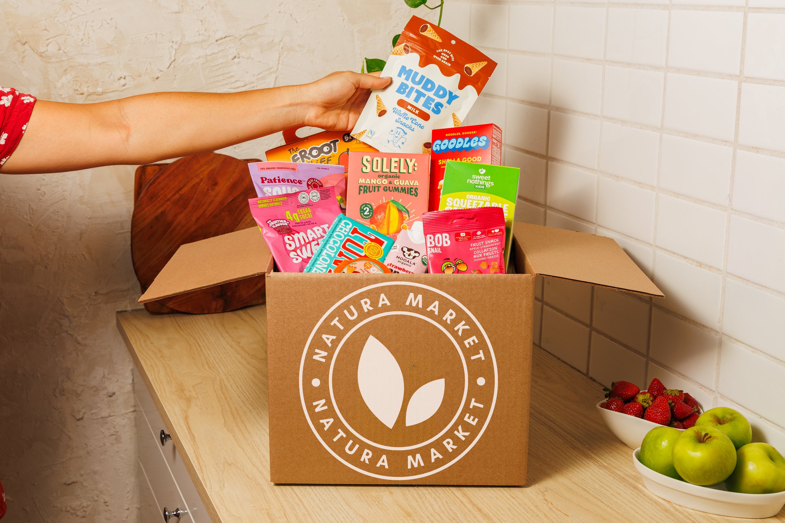 Natura Market box filled with a colourful assortment of packaged snacks and pantry products.