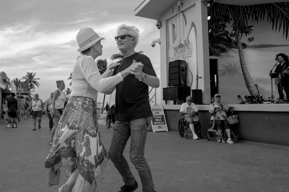 A couple dancing outdoors beside palm trees in black and white