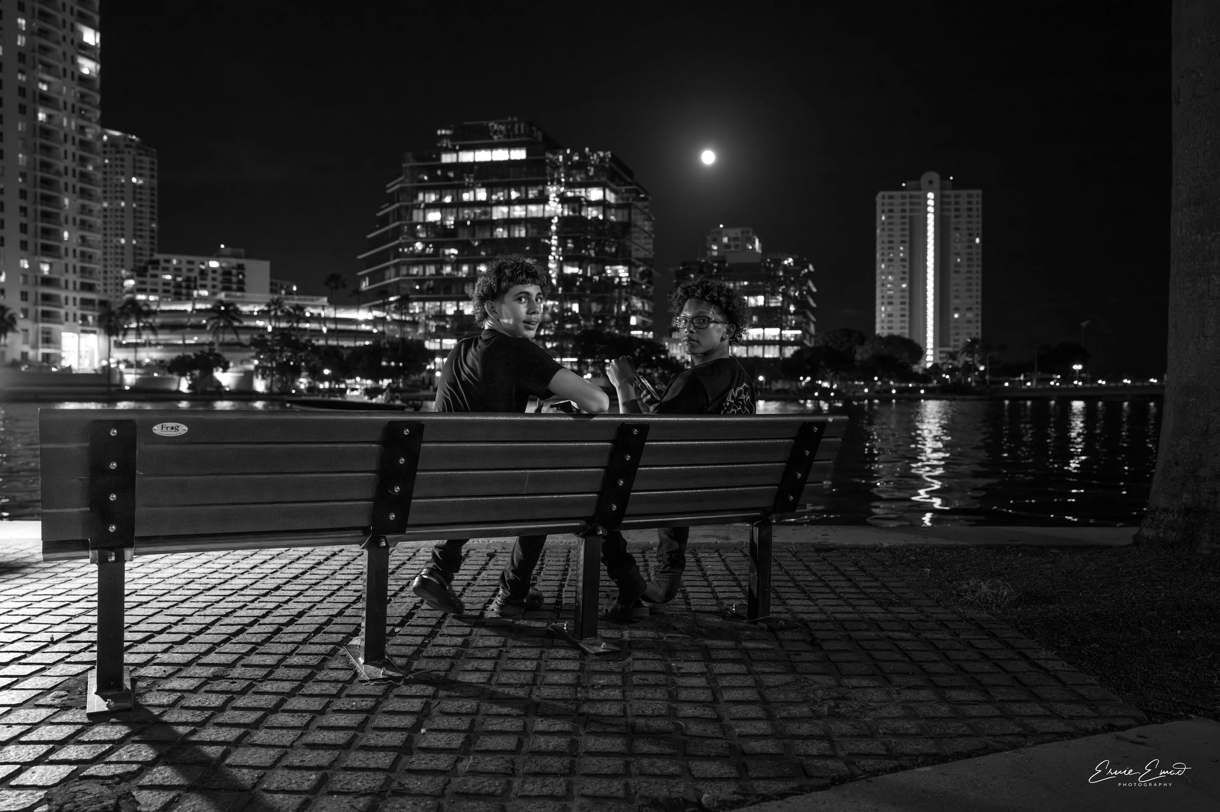 A  full moon over Biscayne bay from Brickell two friends sitting in a bench turned around just as I snapped their picture