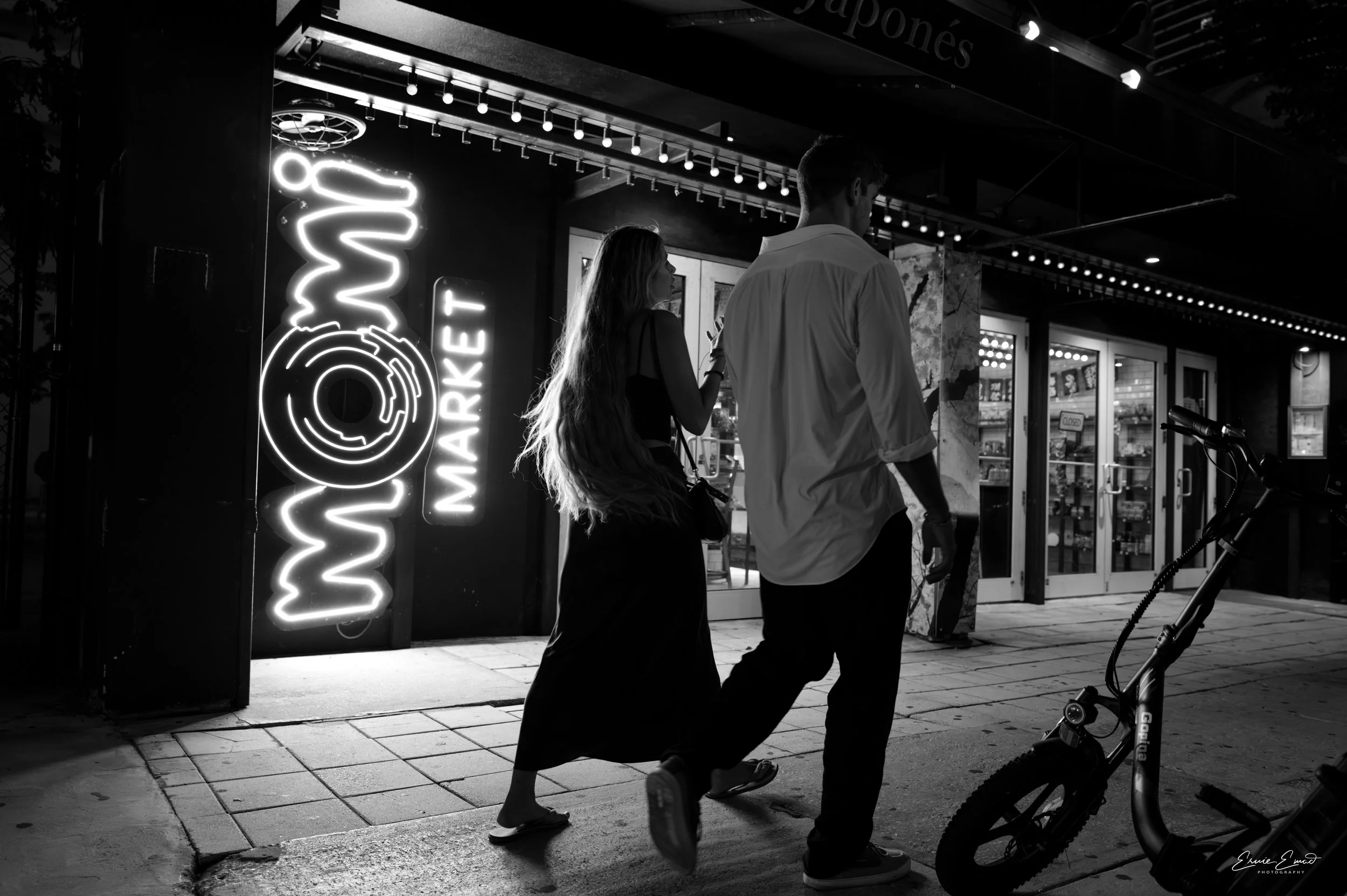Momi market in Brickell was not busy this Friday night as a couple walks past and the neon lights highlight her hair