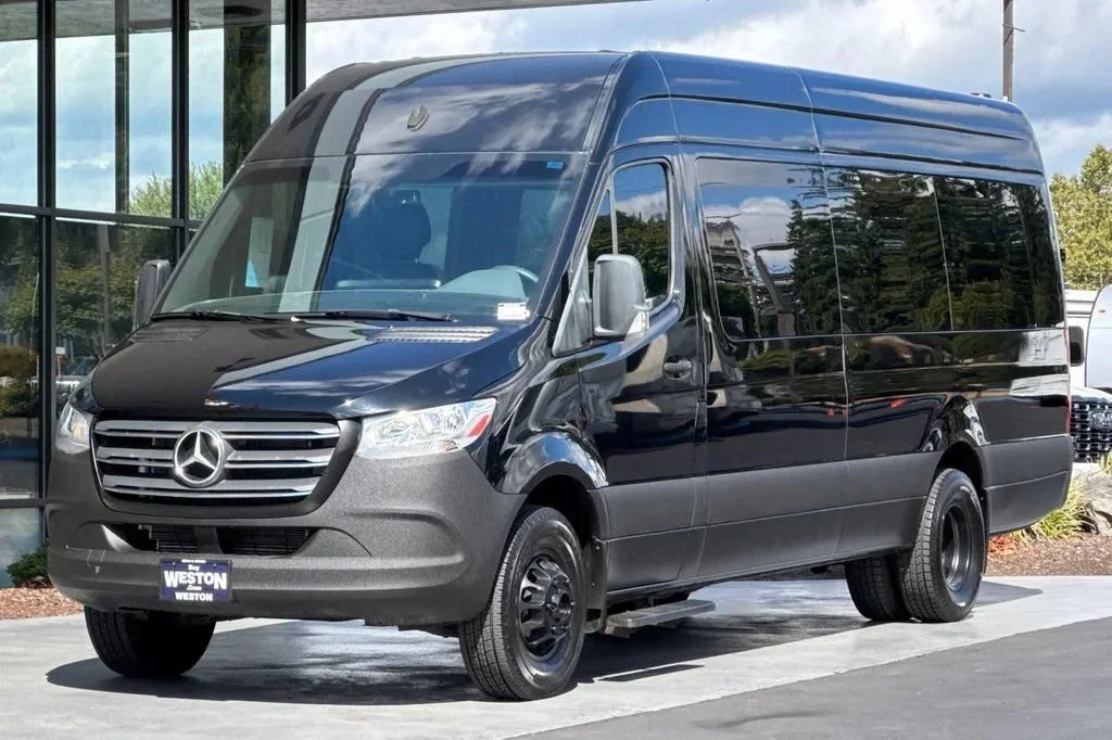 Black Mercedes-Benz van parked outside a building with large glass windows.