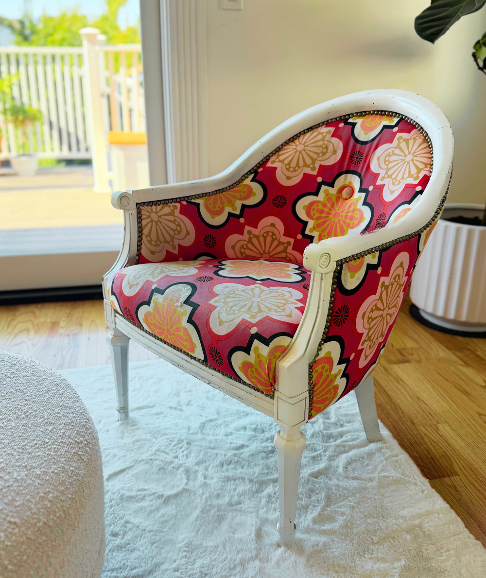 Vintage barrel chair with a white painted frame and vibrant pink floral upholstery