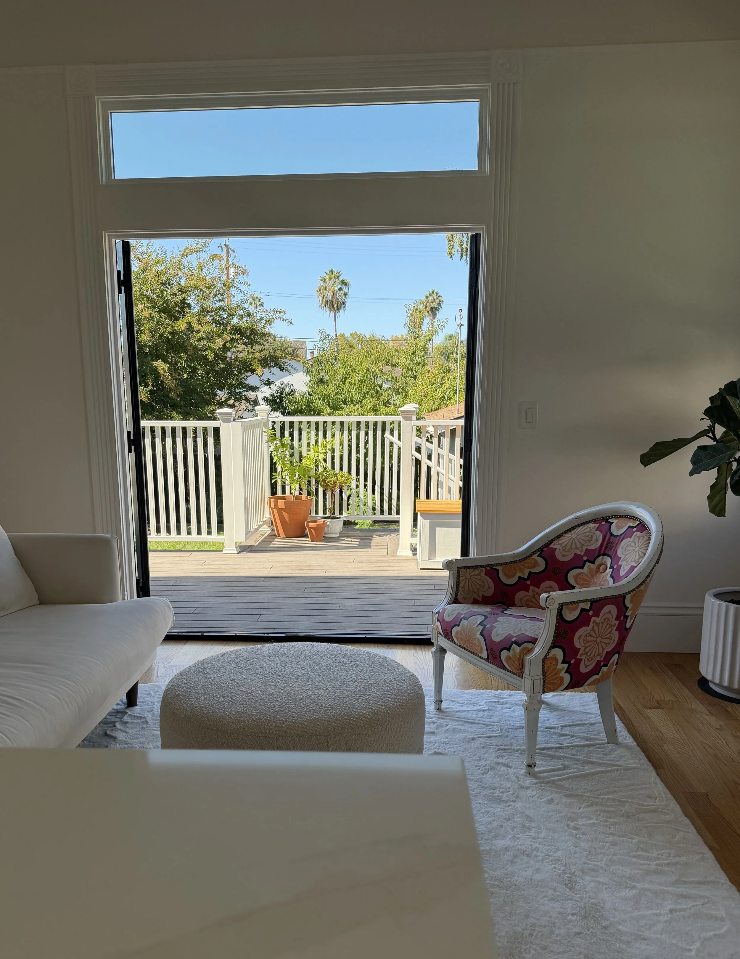 Seating area off kitchen with open French doors and a transom window overlooking the deck and garden.