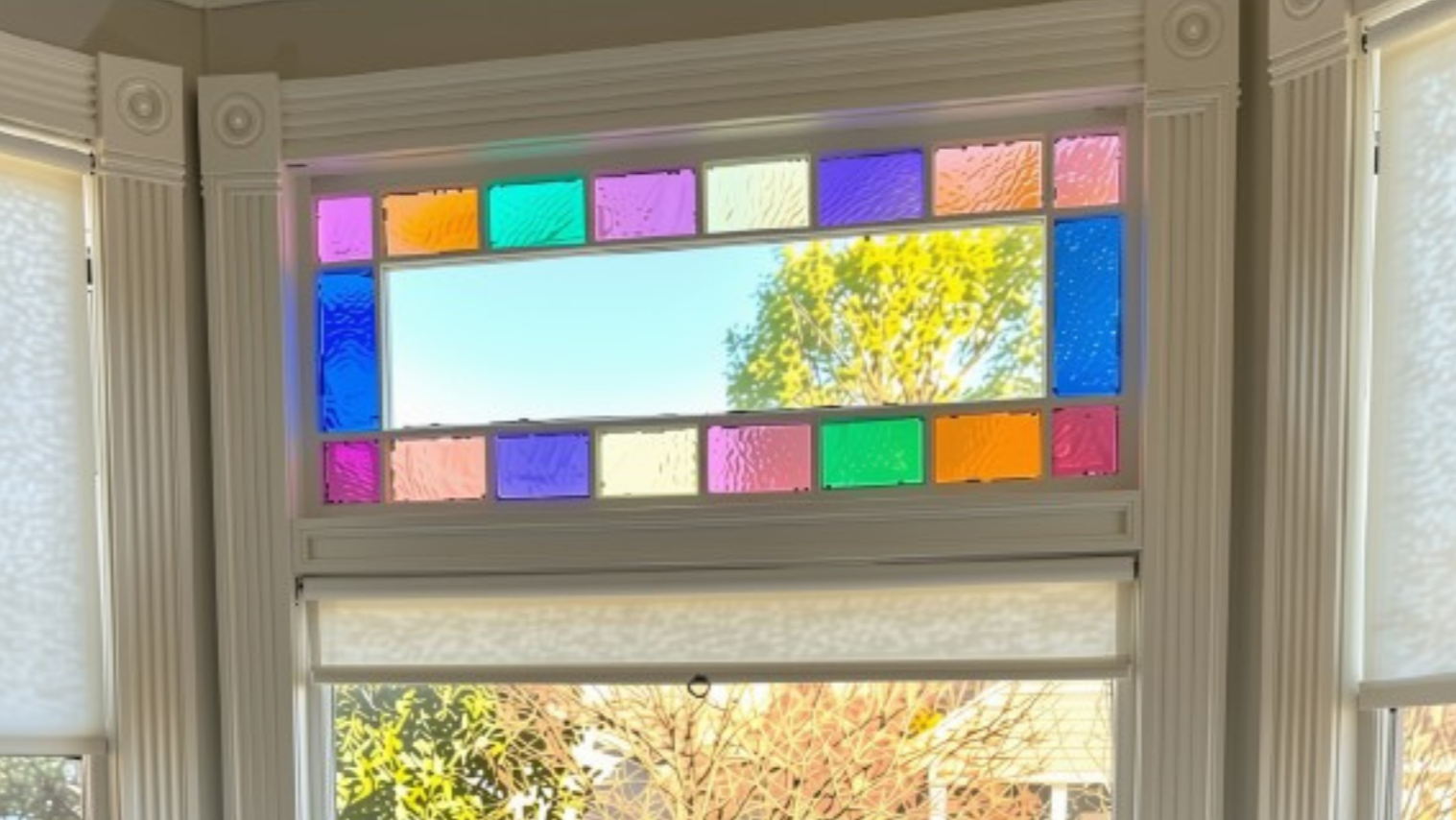 Colorful original stained glass above a window, framed by traditional Victorian moldings