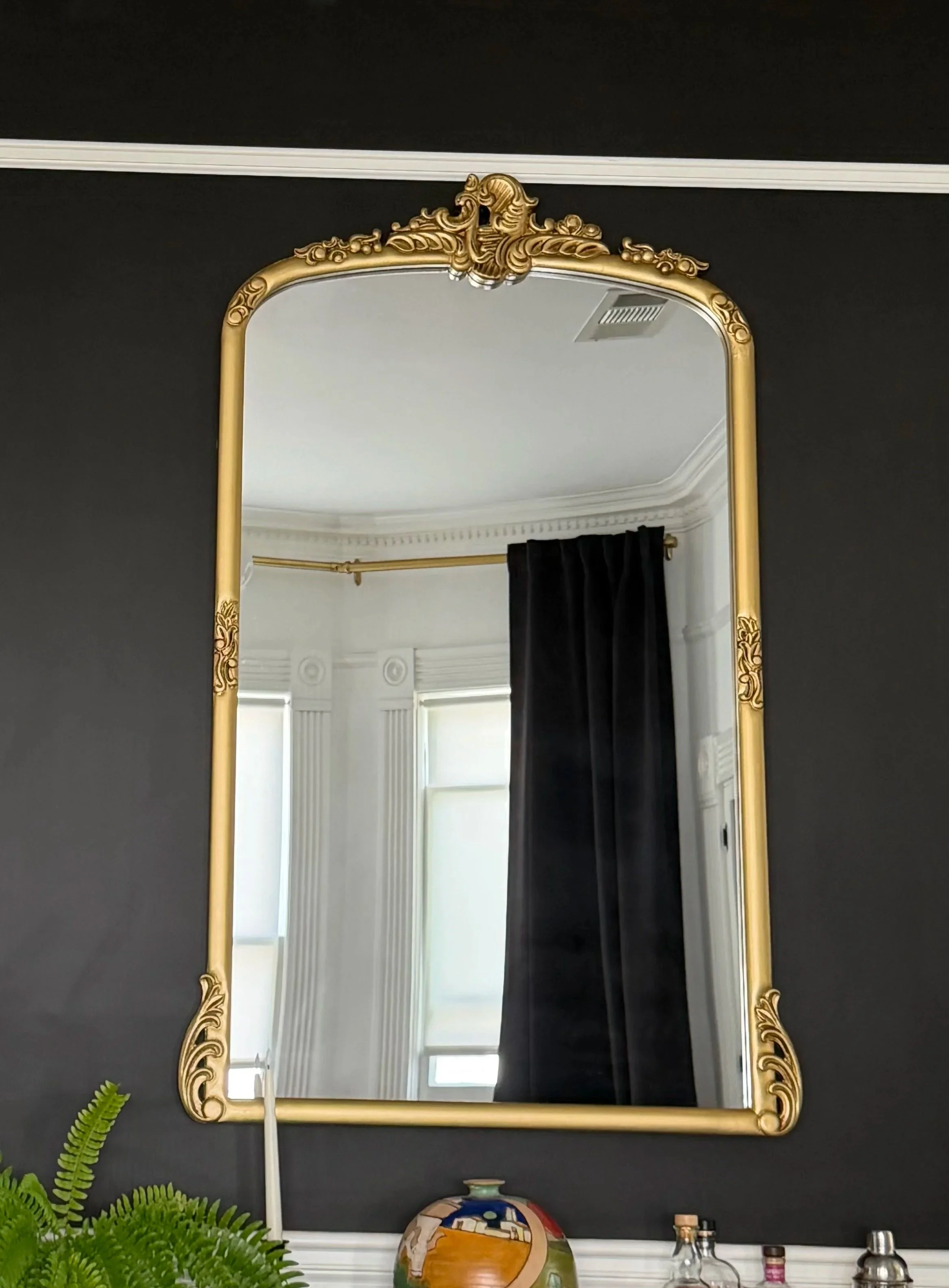Large vintage style gold mirror hanging in a dining room
