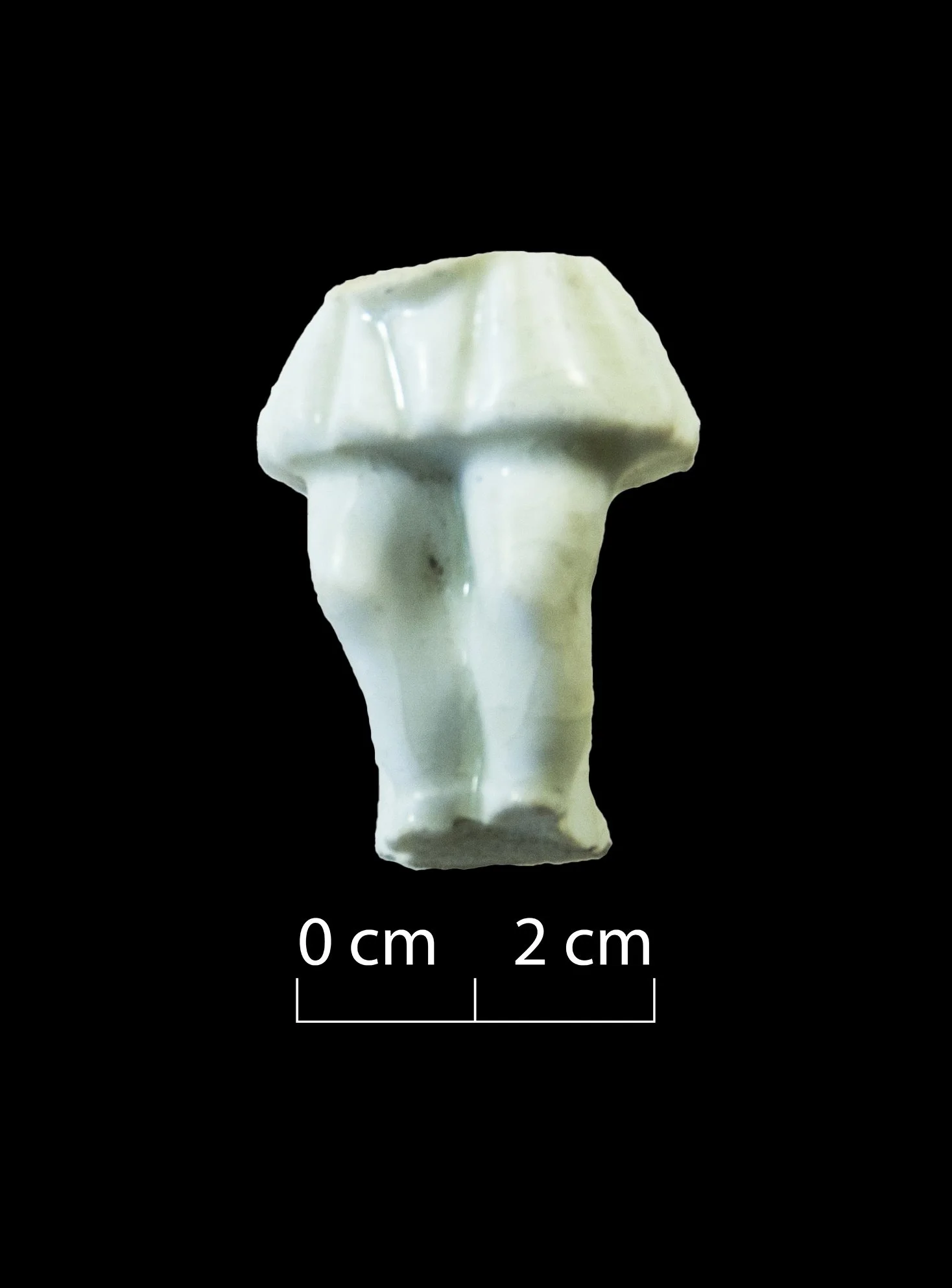 Part of a white porcelain figurine. Appears to be a child. Feet, knees & legs visible, with a short skirt above this. Broken at approximately the waist.