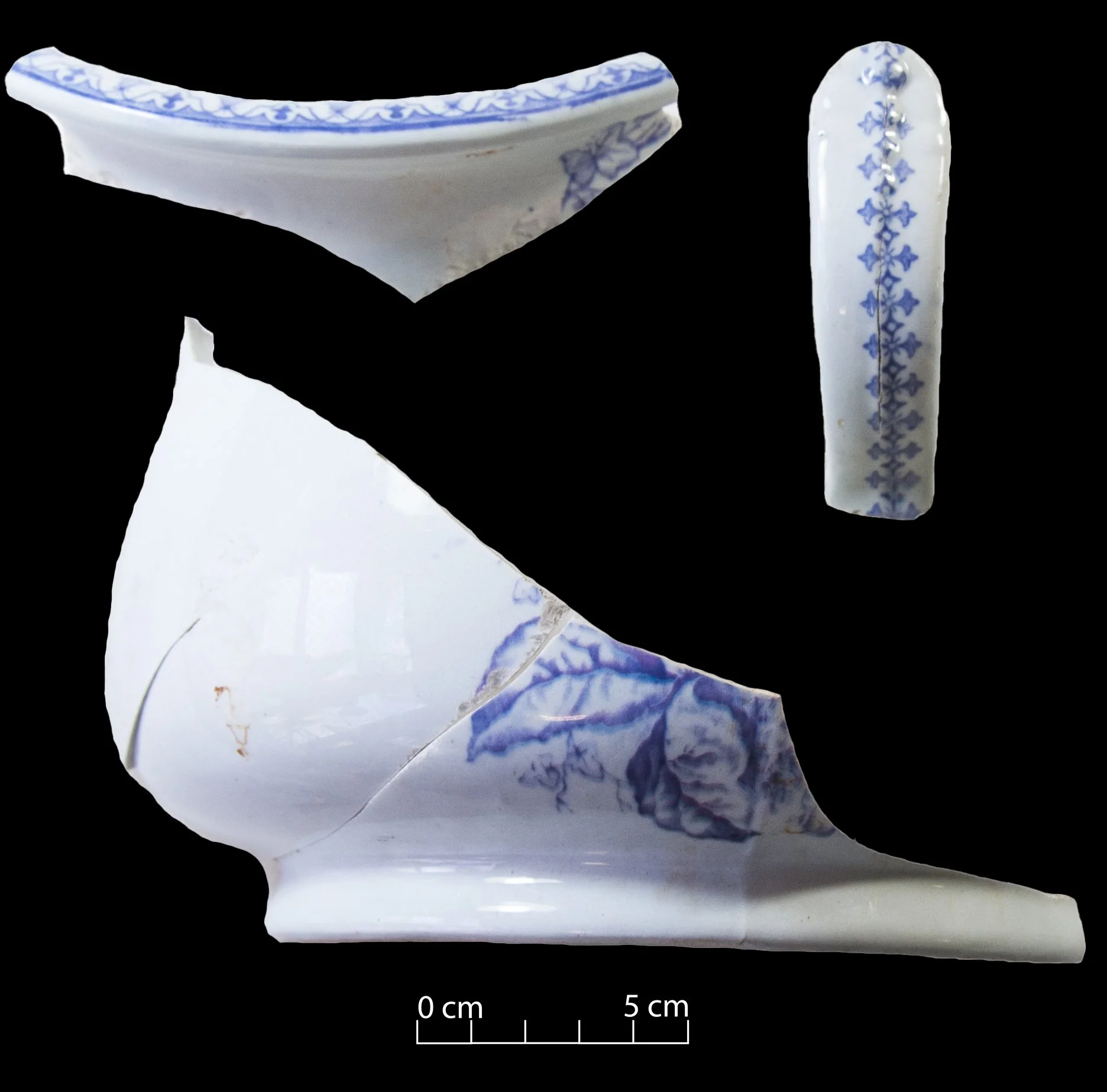 White earthernware chamber pot with purple pattern. Floral on the main body of the vessel, geometric on the handle.