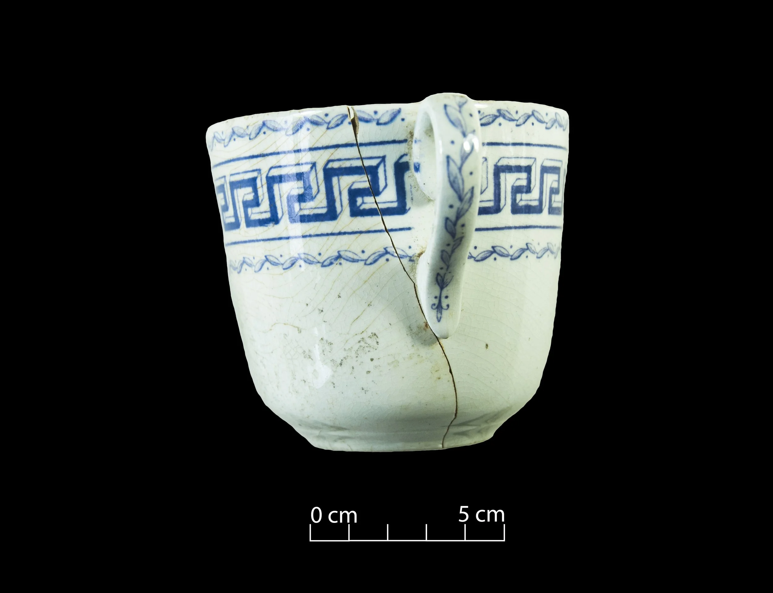 White earthenware tea cup, decorated with a Greek key pattern in blue.