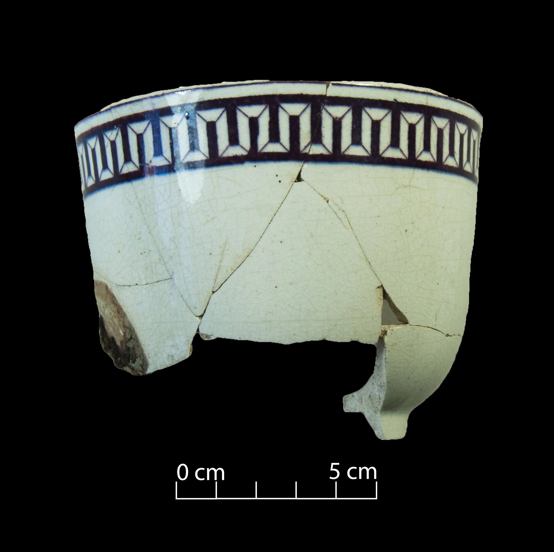 White earthenware tea cup decorated with a Greek key pattern in purple.
