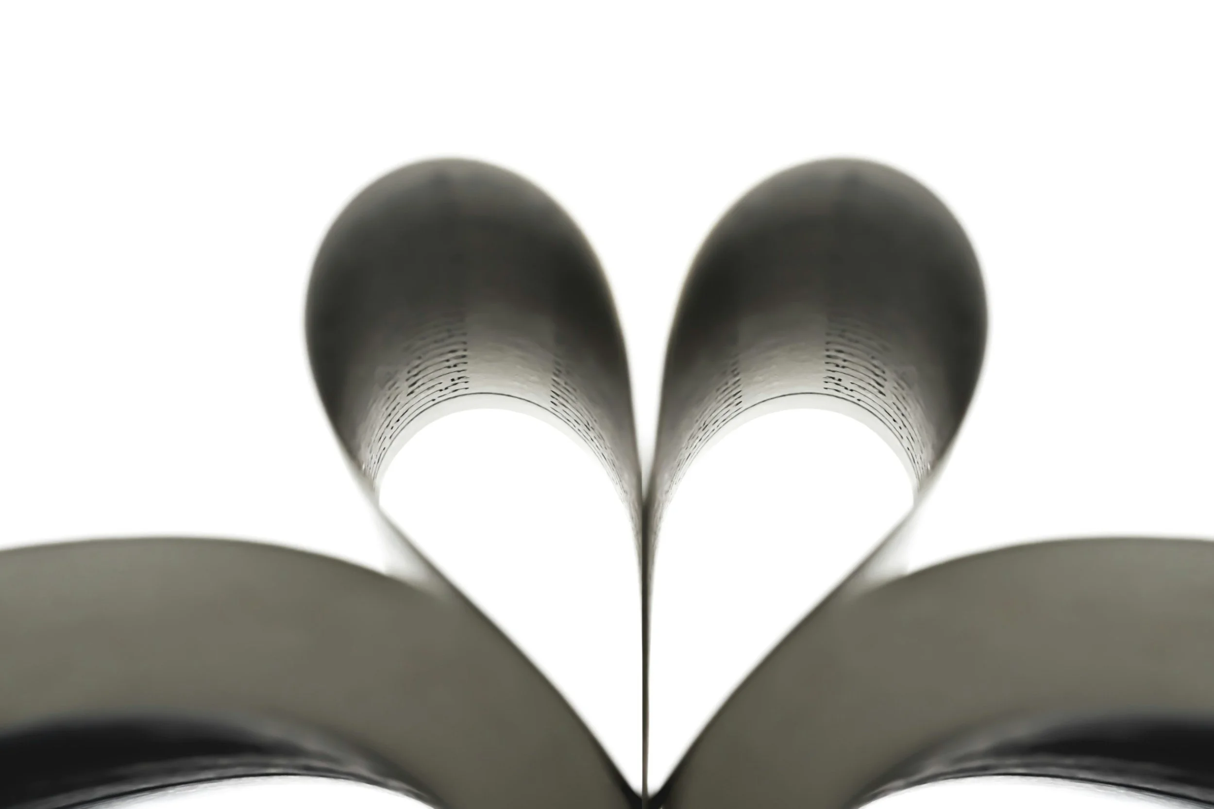 Close-up of a book's pages folded inward to form a heart shape, with the focus on the shape and blurred edges.