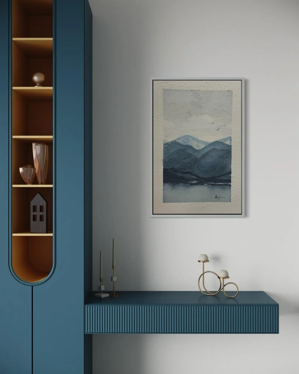 A modern interior with a blue cabinet on the left, displaying decorative vases and a small house-shaped ornament, a wall-mounted blue shelf, a framed landscape painting of mountains and water, and a minimalist gold and white sculpture on the shelf.