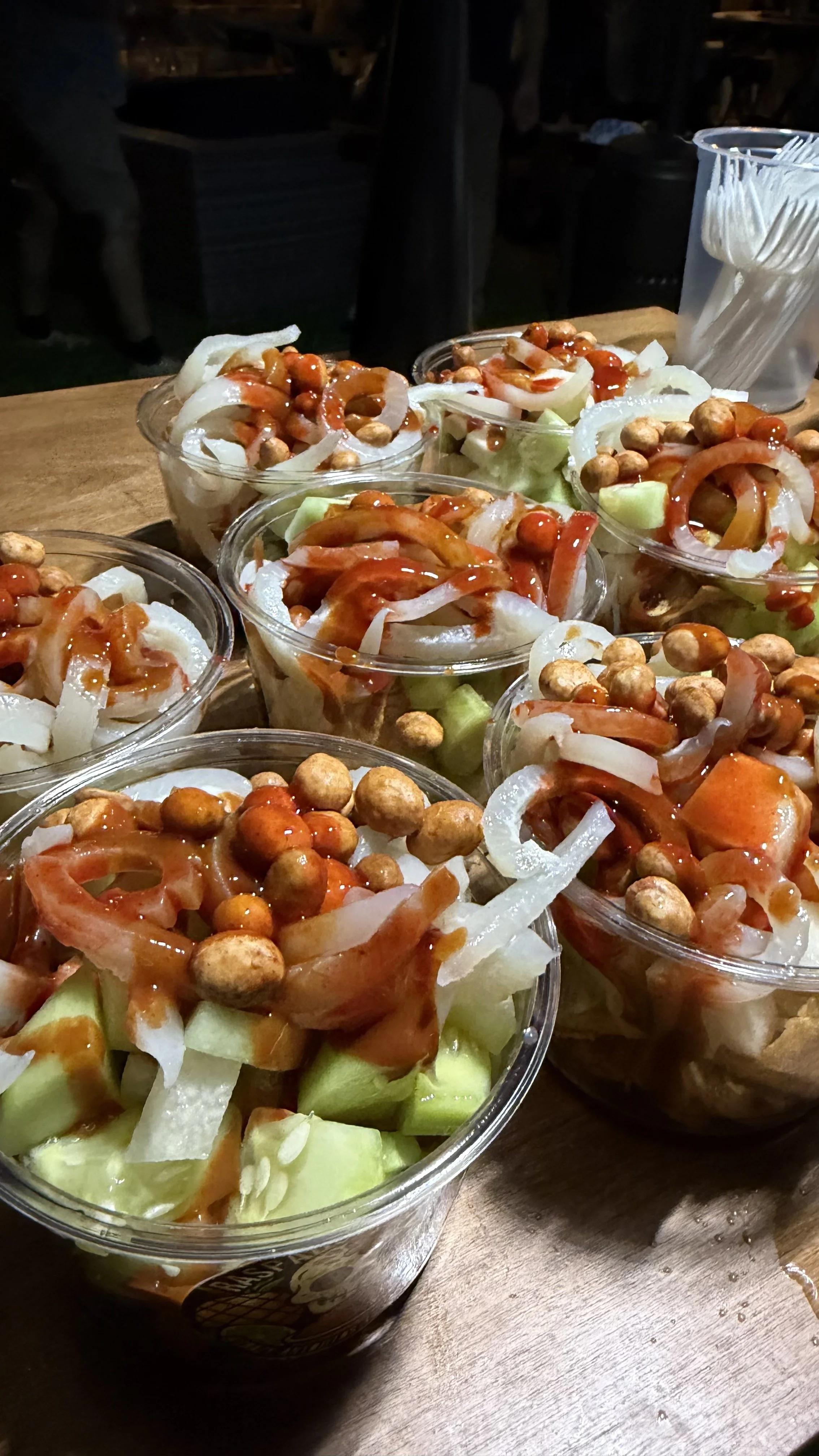 Several bowls of salad with chopped onions, chickpeas, and sauce on a wooden table.