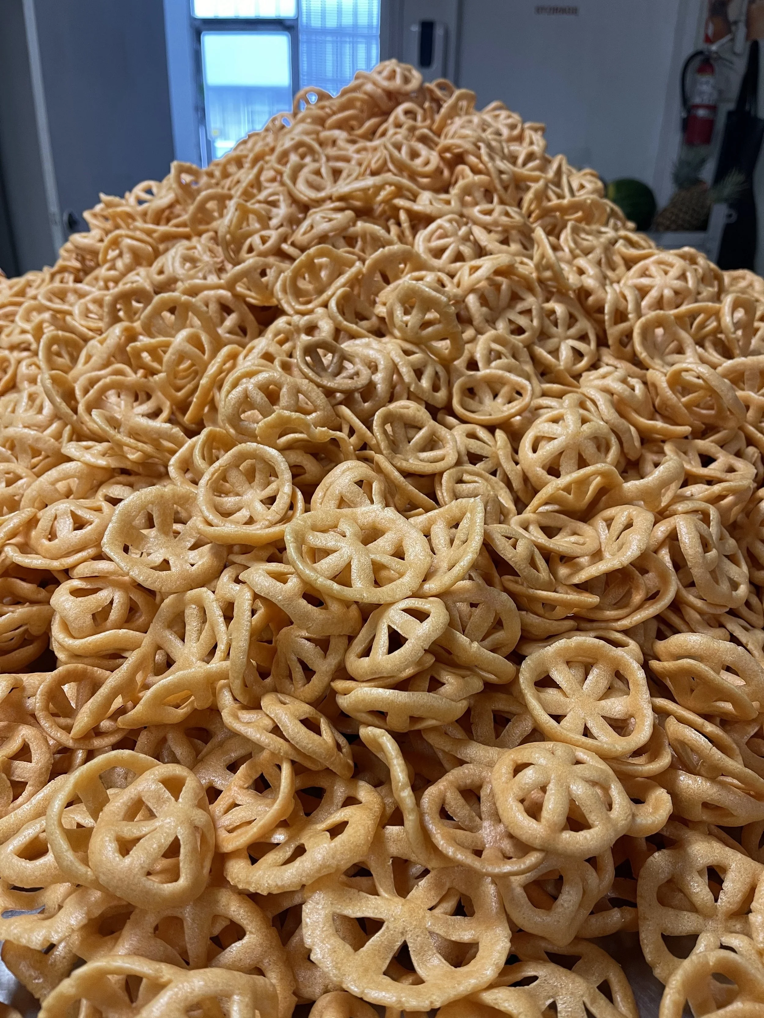 A large pile of pretzels in an indoor setting with windows and a door in the background.