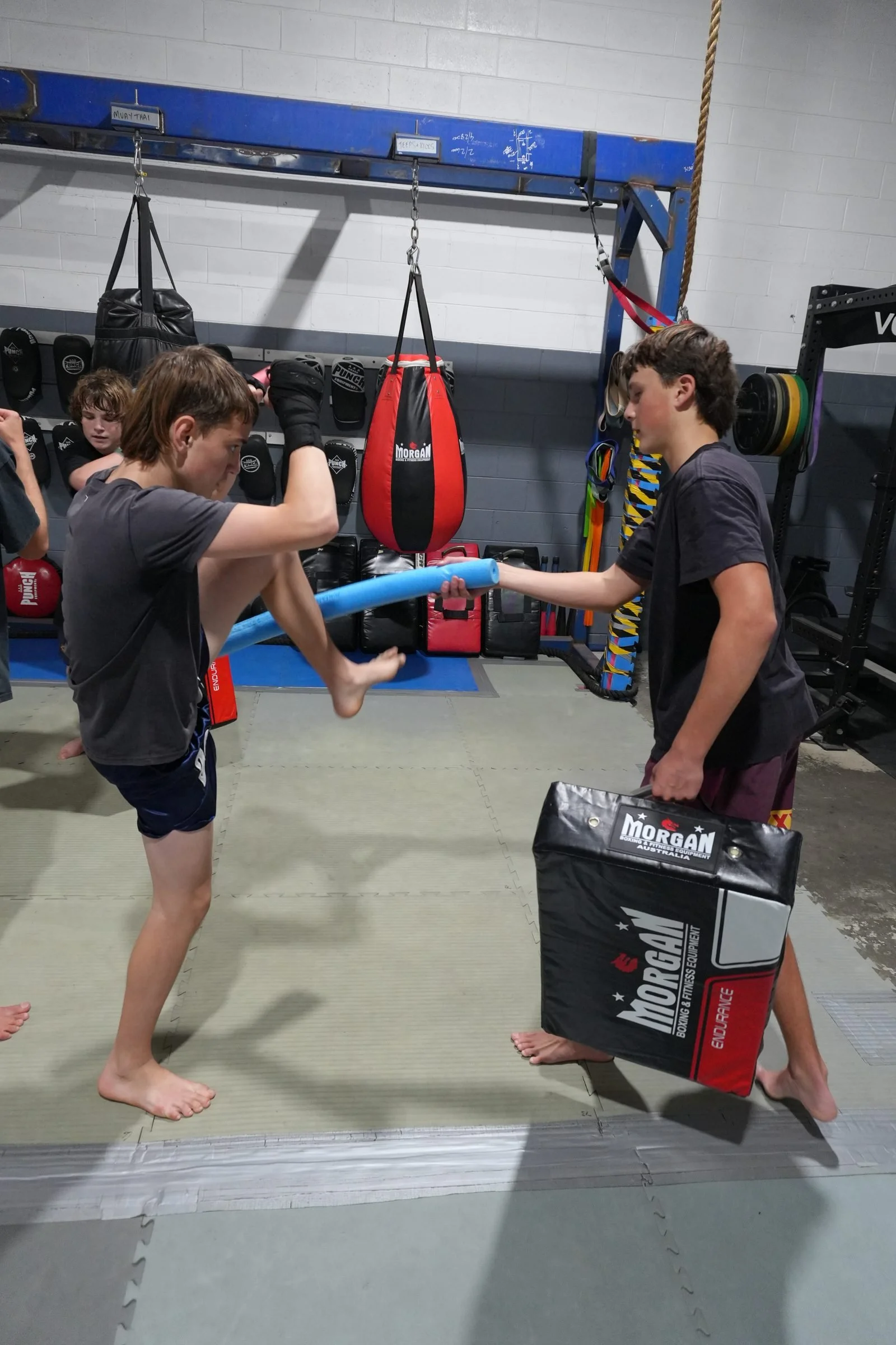Teens practising kicks and knees on strike shields in a teens Muay Thai class, Tweed Heads