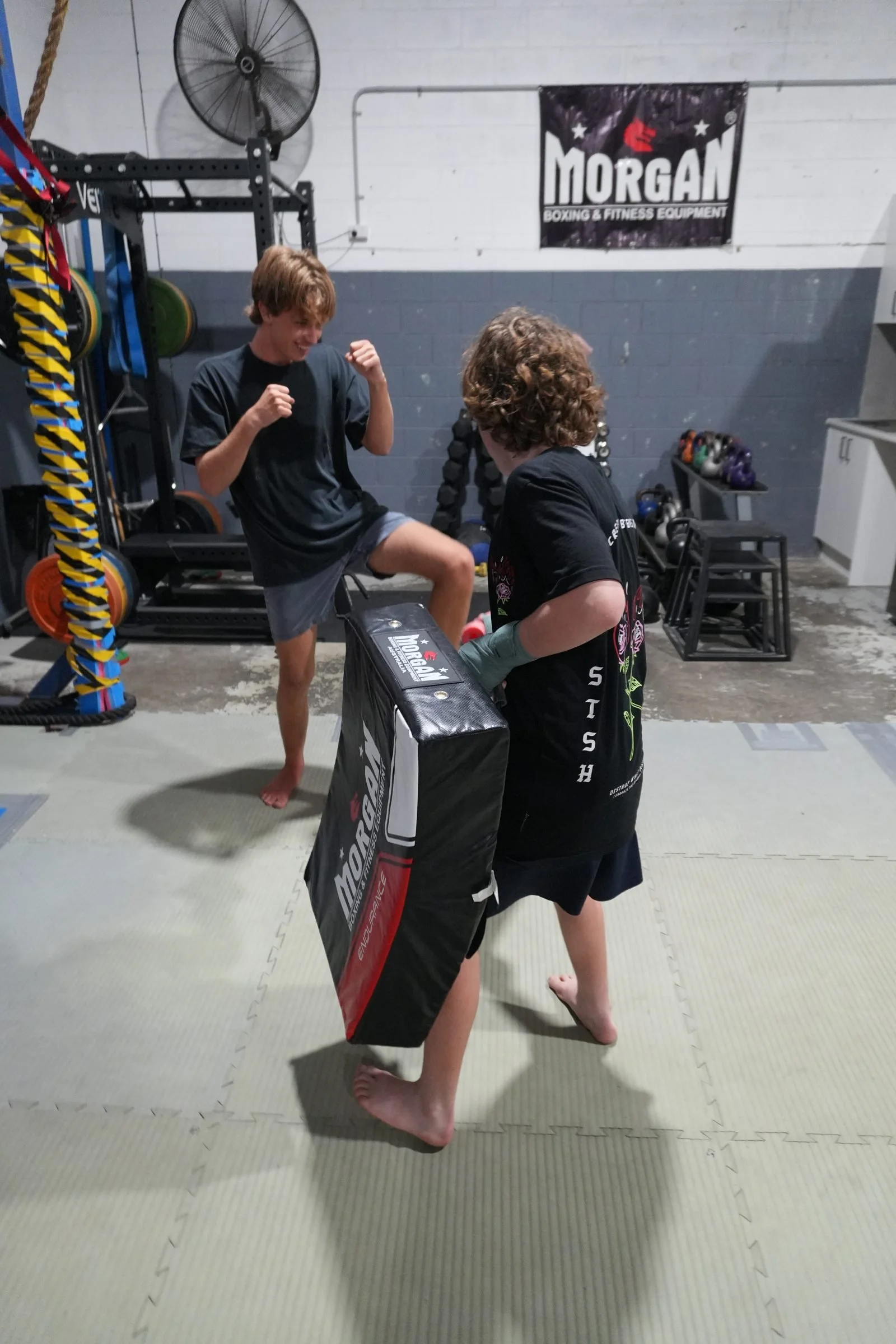 Muay Thai student in gloves and shin guards resting between rounds at DM Muay Thai & Fitness, Tweed Heads