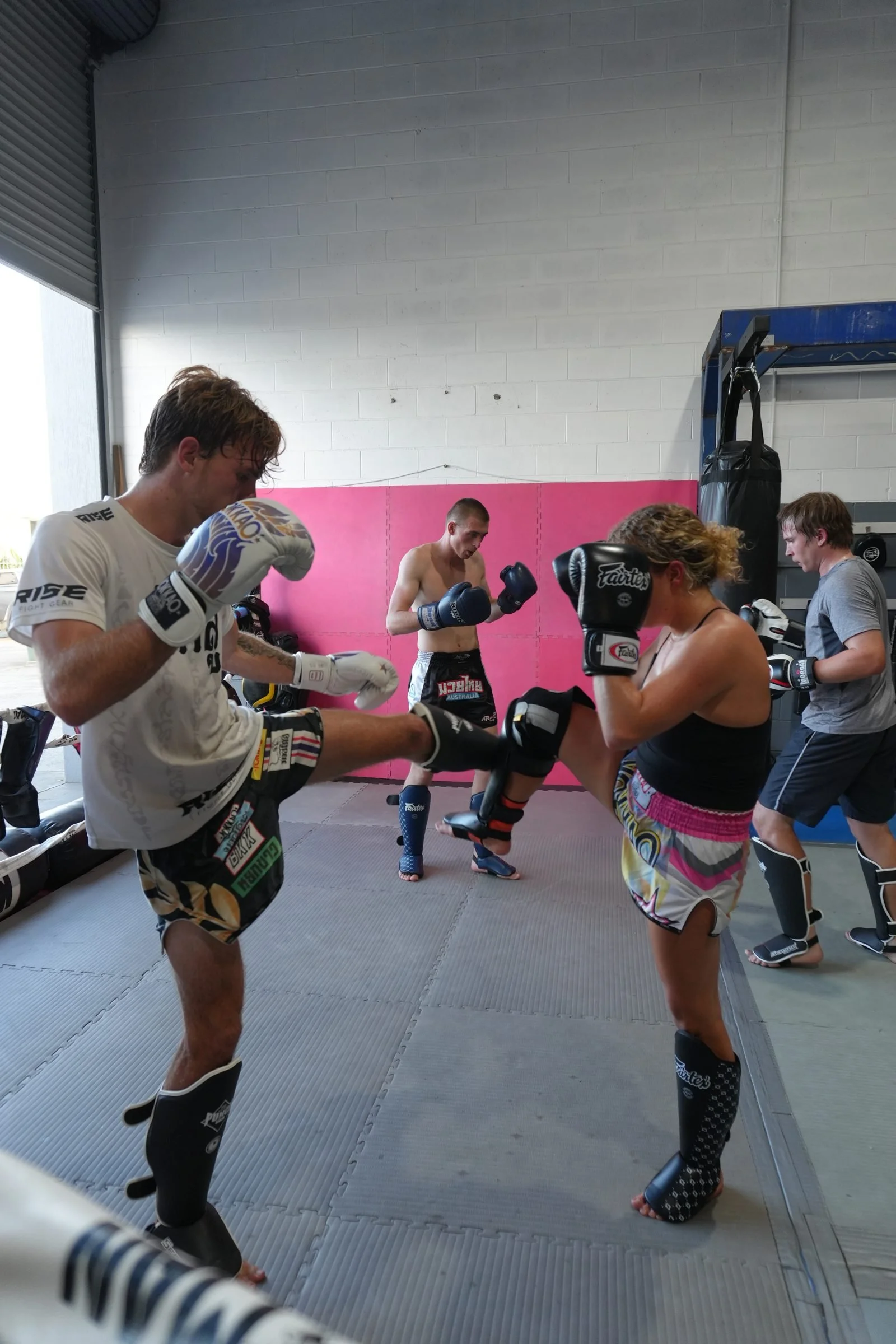 Partners drilling kicks in shin guards during an all levels Muay Thai class in Tweed Heads