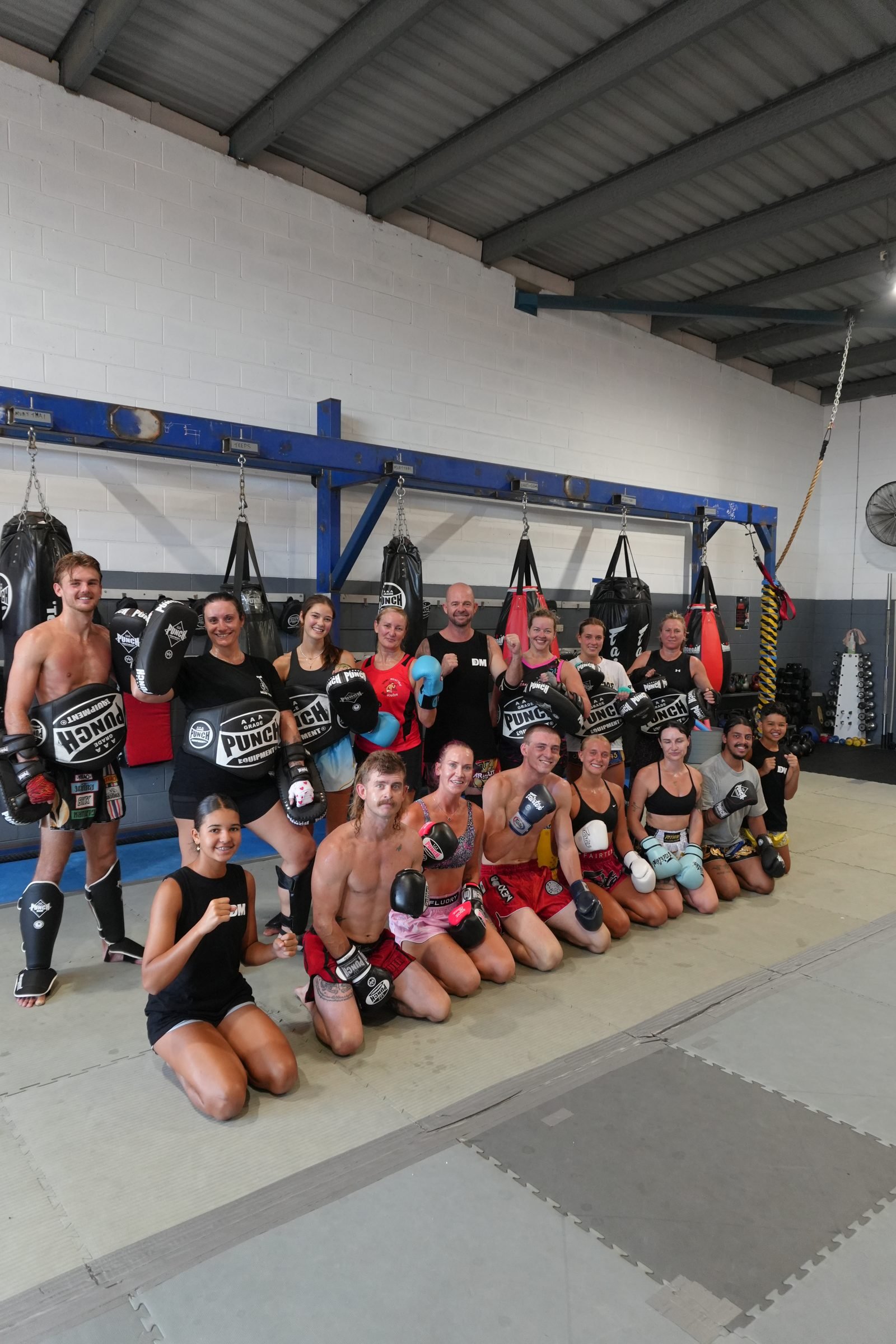 Group of adult Muay Thai members kneeling together on the mats at DM Muay Thai & Fitness, Tweed Heads