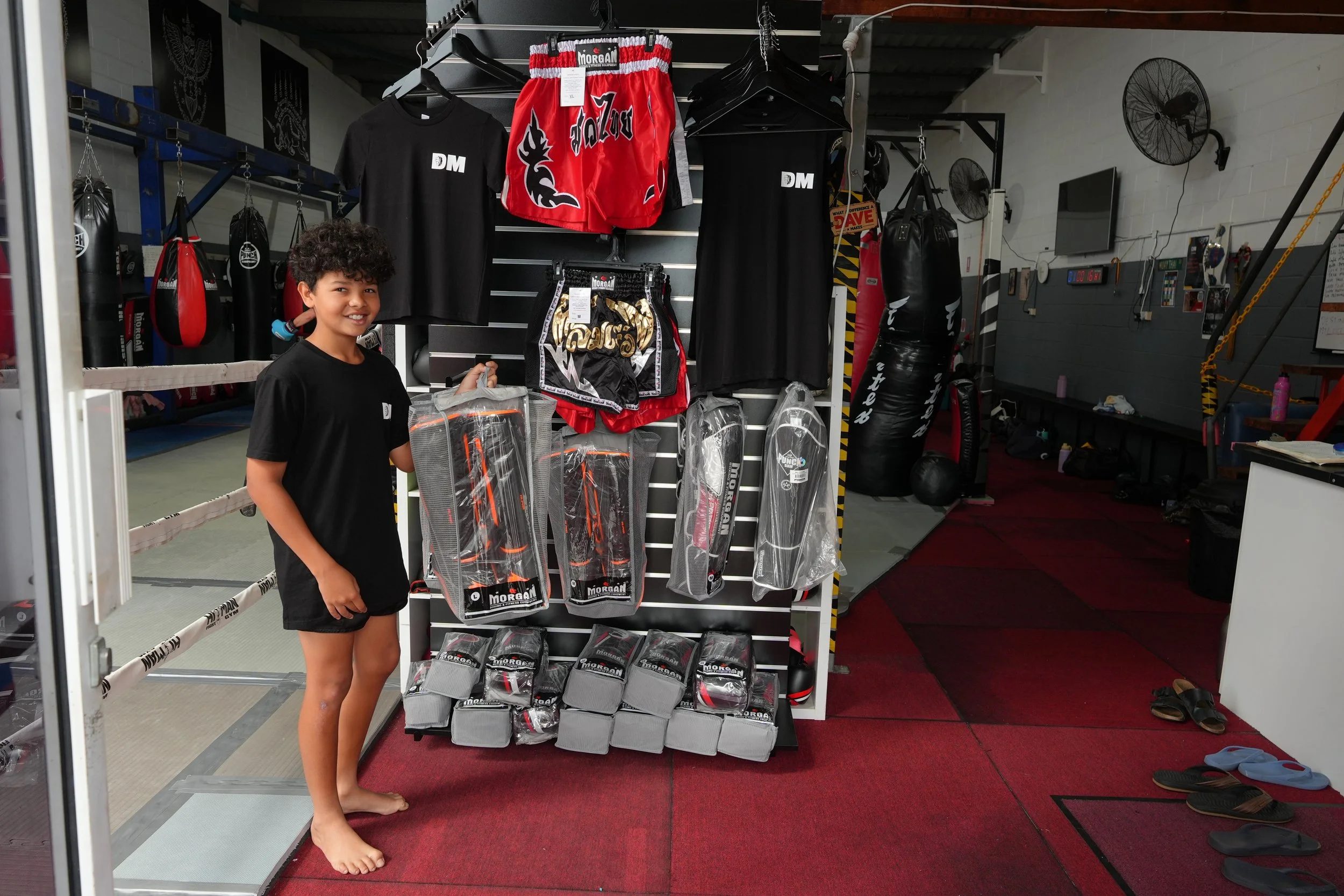 Boxing gloves, shin guards and Muay Thai shorts on the gear rack at DM Muay Thai & Fitness