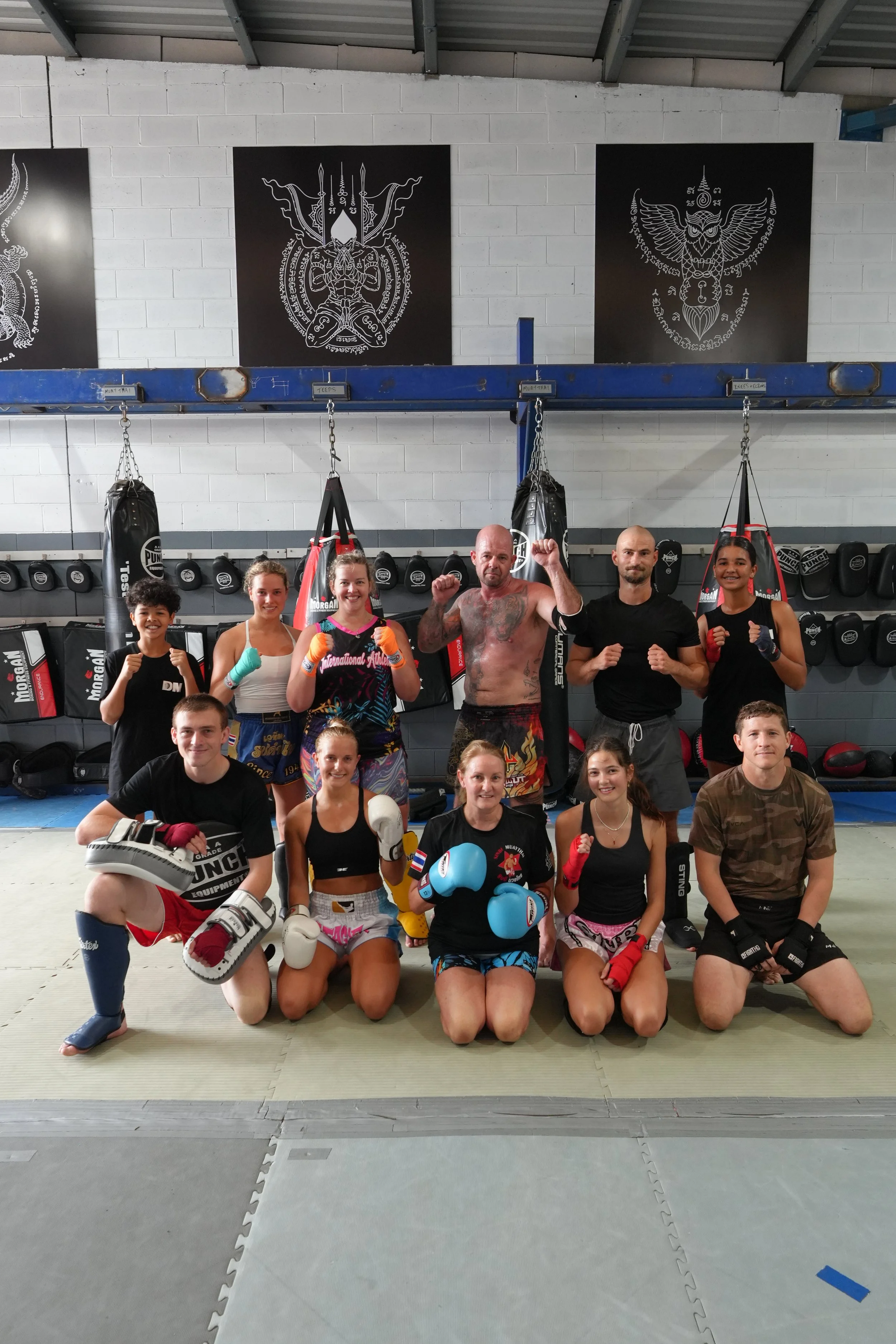 Group photo of the DM Muay Thai & Fitness crew in front of the boxing ring