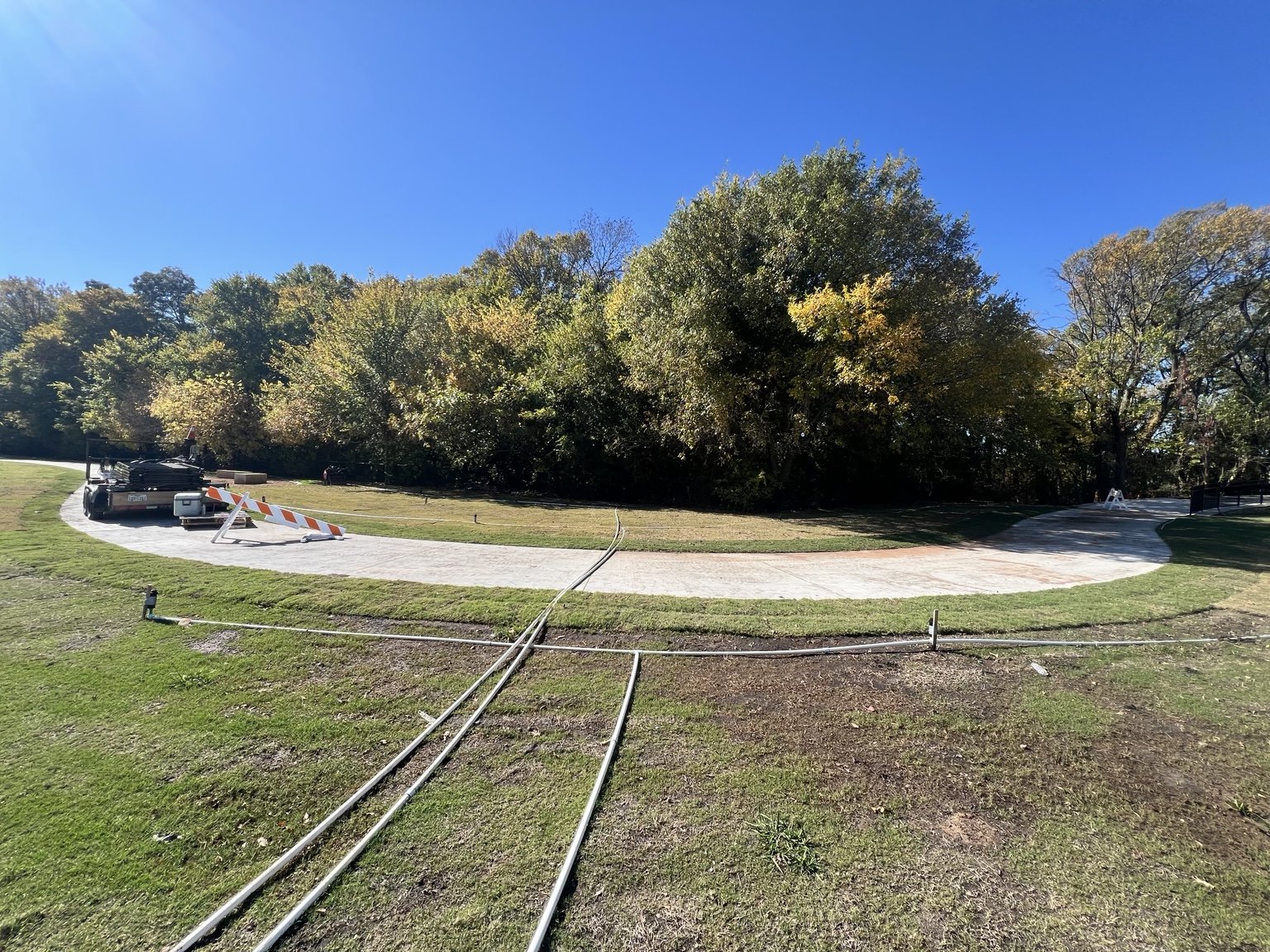 Trail landscaping — sod and temporary irrigation beside the curved concrete path.