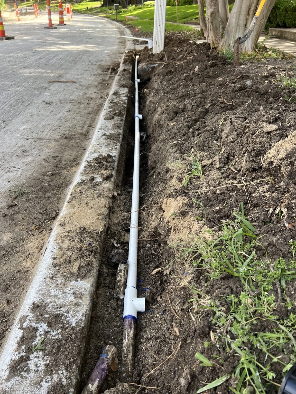Construction progress — irrigation line replacement along the curb.