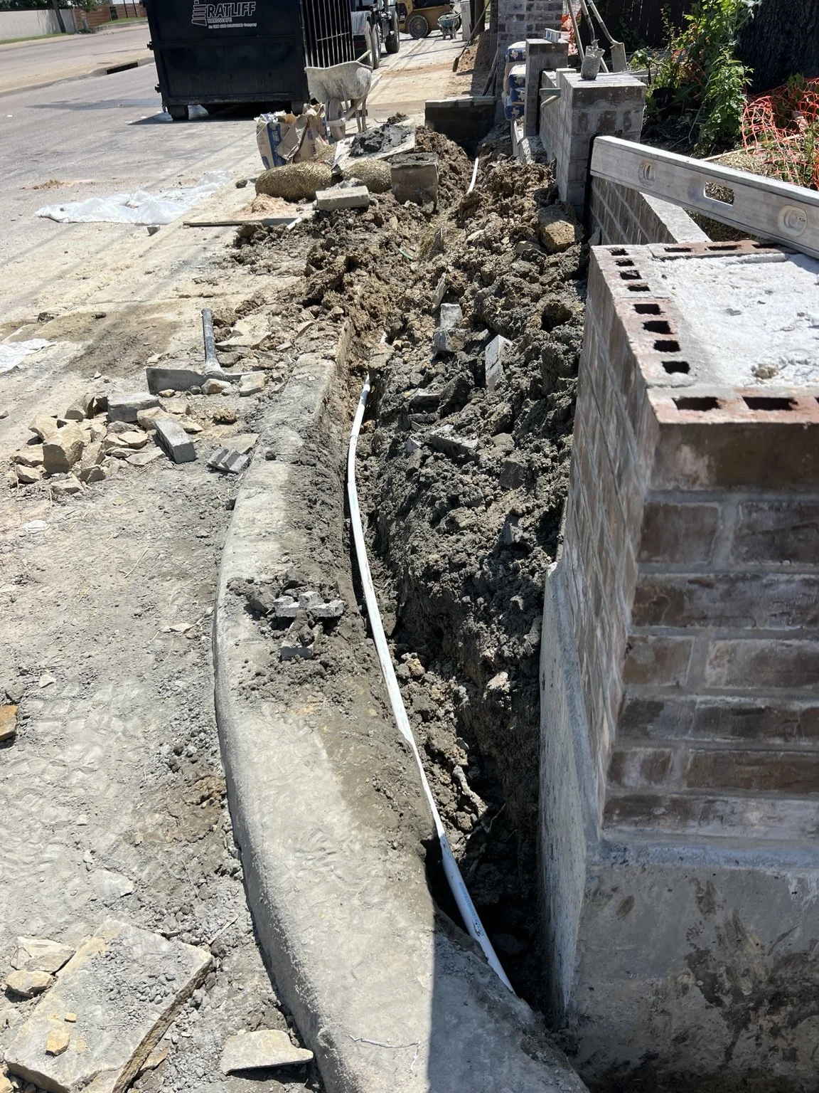 Construction progress — irrigation pipework beside the screening-wall work.