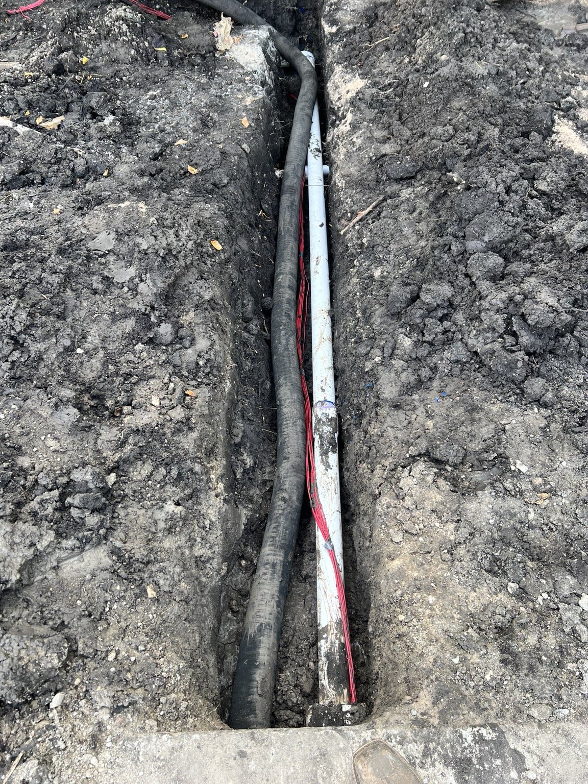 Irrigation installation detail — PVC piping and control wiring in the trench.