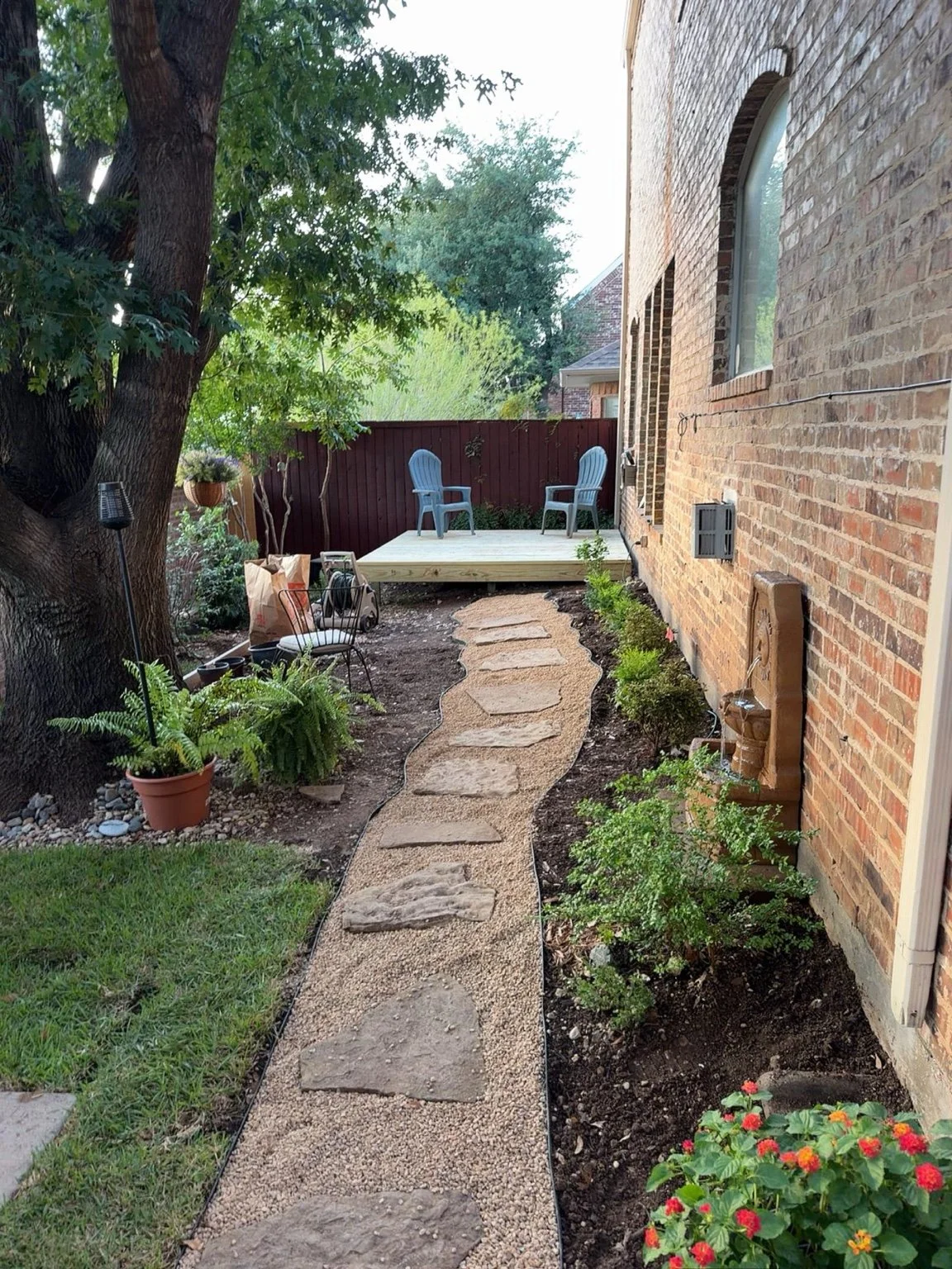 Residential landscaping — gravel garden path, stepping stones, and planting beside a wood deck.