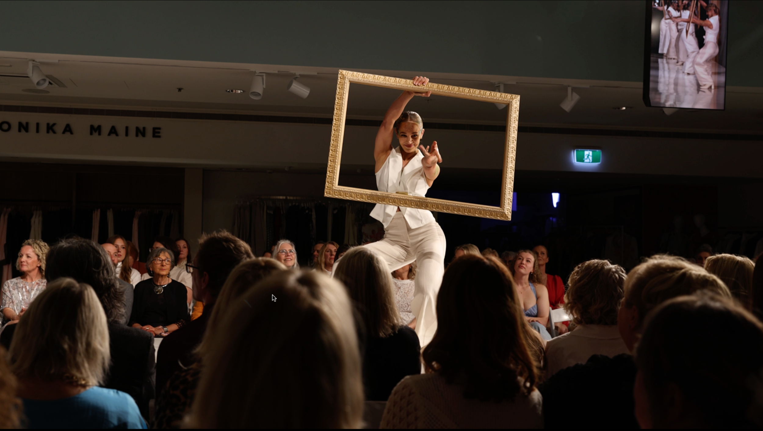 Dancer posing through picture frame on the runway