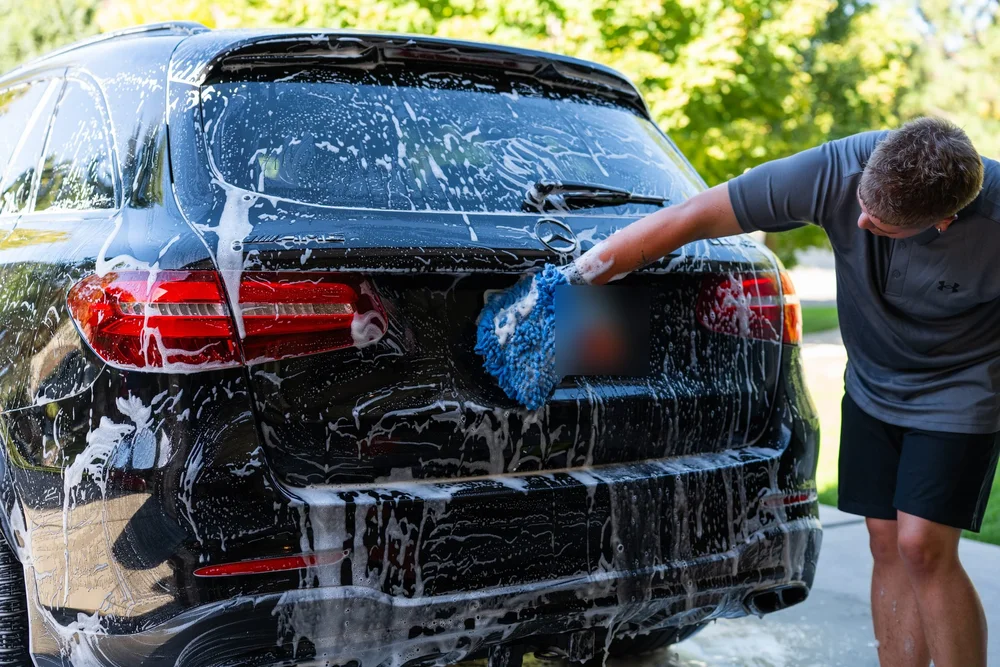 Hand washing the back of an SUV with a wash mitt
