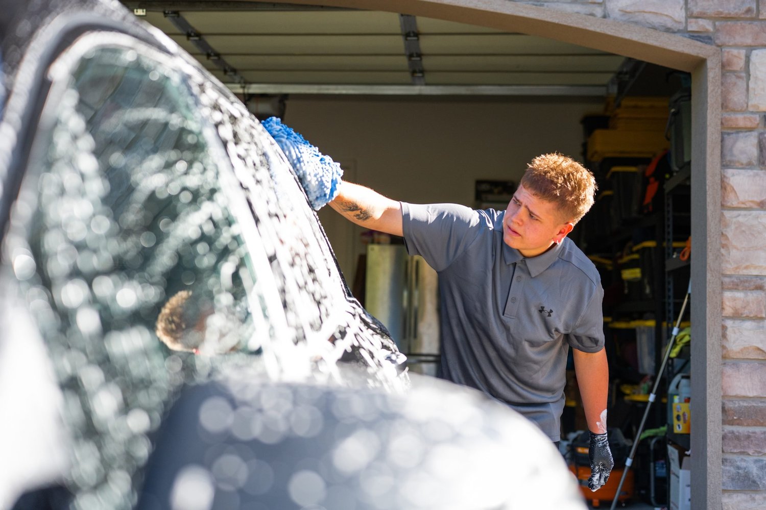 Hand washing a car window with a wash mitt