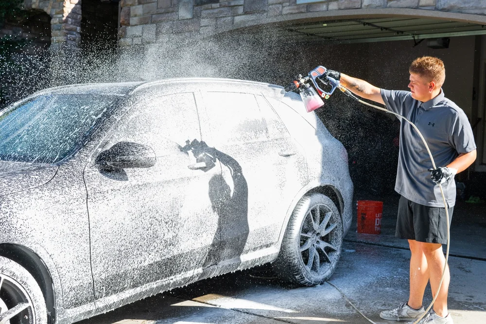 Foam cannon pre-wash on a black Mercedes SUV in a driveway