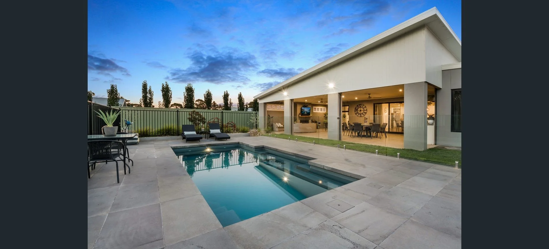 Landscaped backyard with swimming pool, stone paving and outdoor entertaining area.