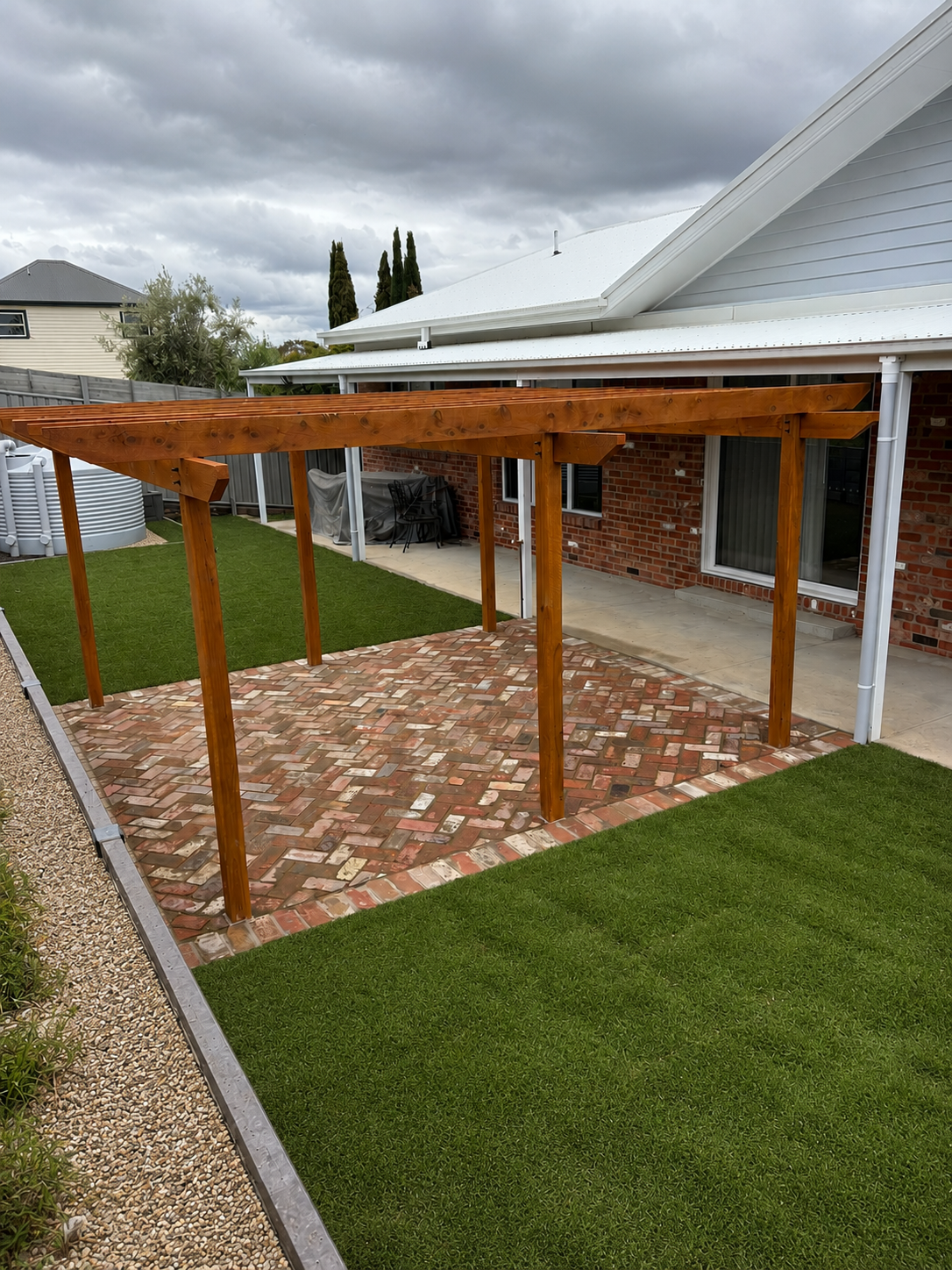 Timber pergola with reclaimed brick paving and newly laid turf in a landscaped backyard.