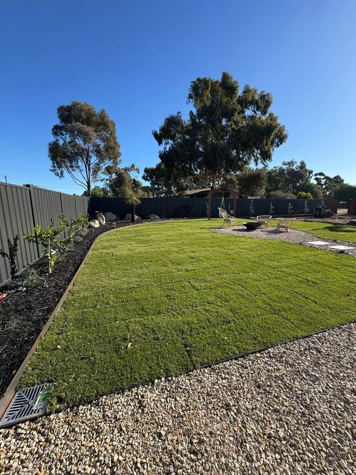 Landscaped backyard with established lawn, garden beds and outdoor fire pit area.