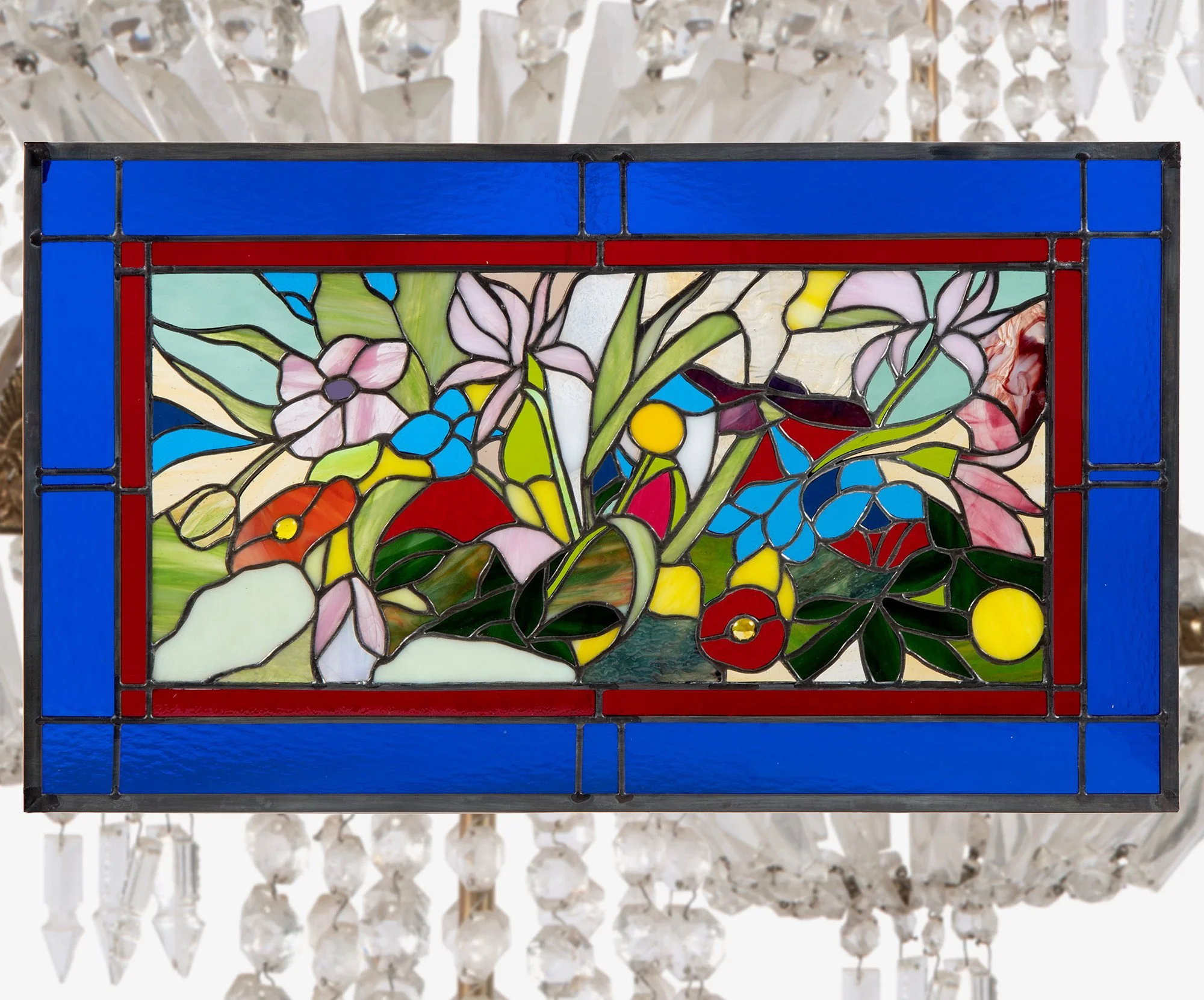 A horizontal stained-glass window of pink, blue, orange, and yellow flowers with green leaves, surrounded by red and deep blue borders.