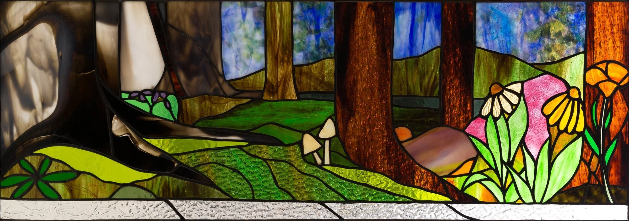A wide stained-glass woodland scene with tree trunks, green ground, flowers, and mushrooms.