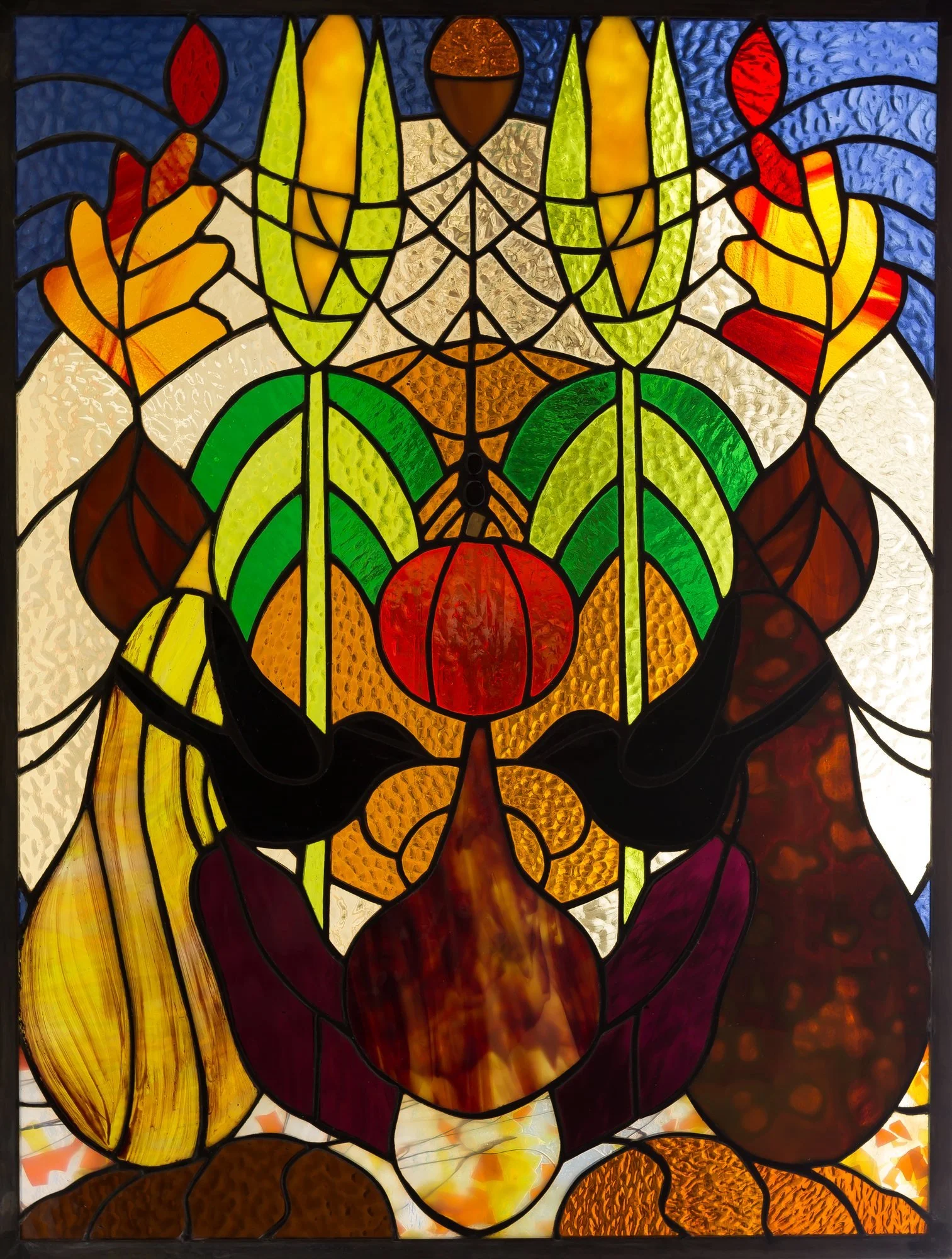 A symmetrical stained-glass arrangement of fruit, leaves, and warm autumn colors.