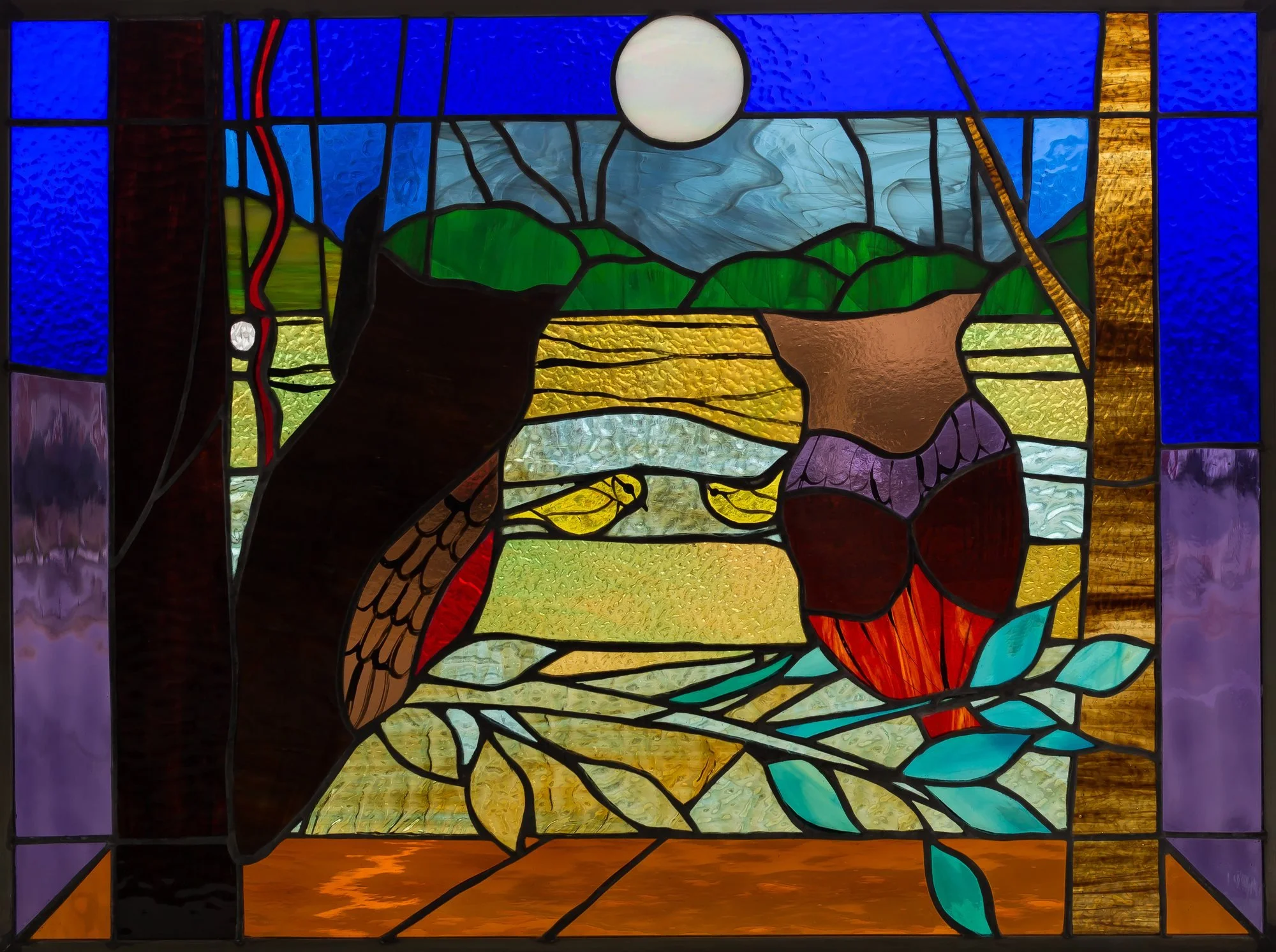 Two owls in a stained-glass woodland scene beneath a pale moon and a deep blue border.