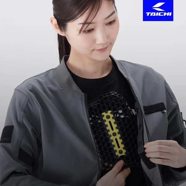 Woman wearing a black shirt and gray jacket holding a honeycomb-like device with yellow components.