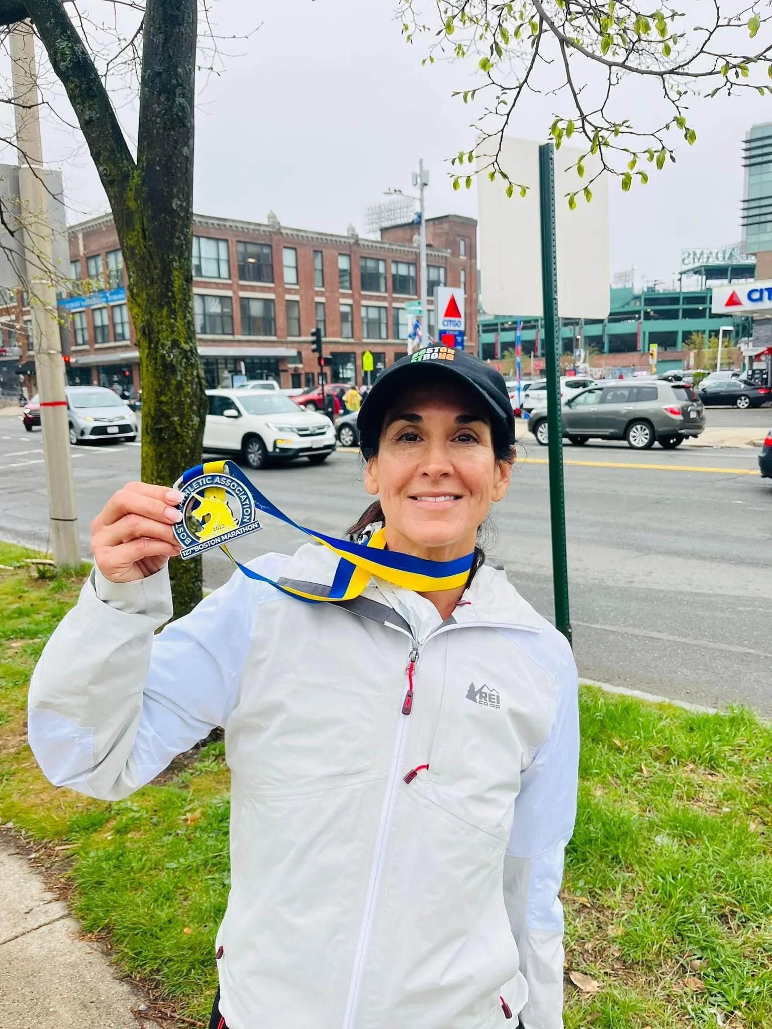 Gloria displaying her finisher medal after completing the Boston Marathon.