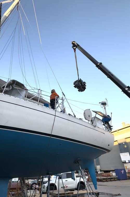 Person on a boat using a crane to lift equipment during maintenance or repair.