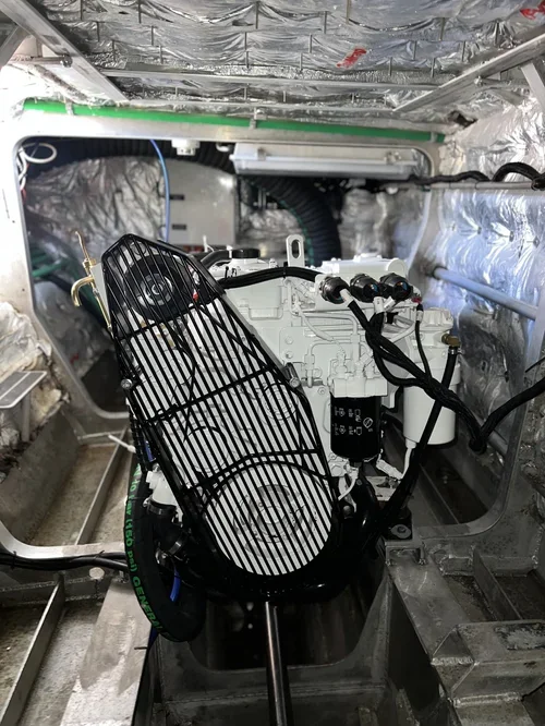 Close-up view of machinery inside an aircraft with insulation, wiring, and metal components, including a protective wire cage covering part of the equipment.