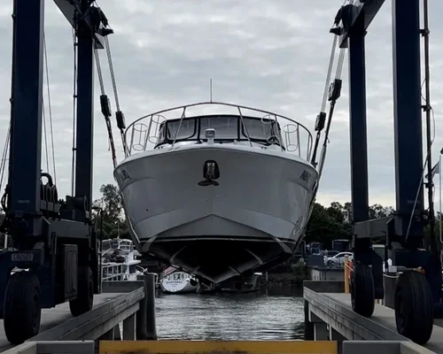 A boat docked in a boat lift at a marina with other boats visible in the background.