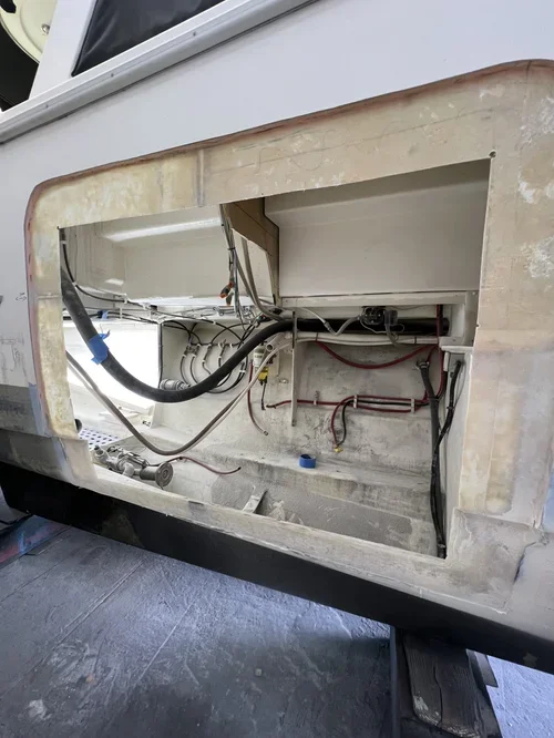 The image shows the interior of a partially disassembled white machine or device, exposing various wires, tubes, and internal components.