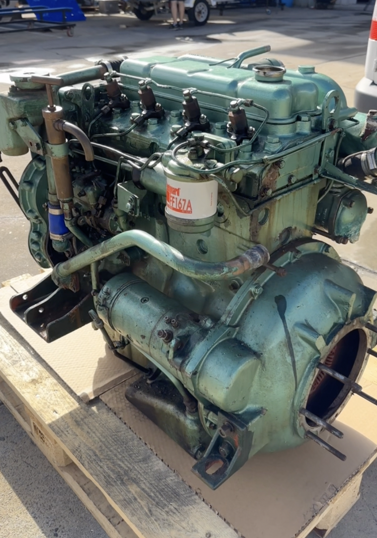 An industrial diesel engine on a wooden pallet outdoors.