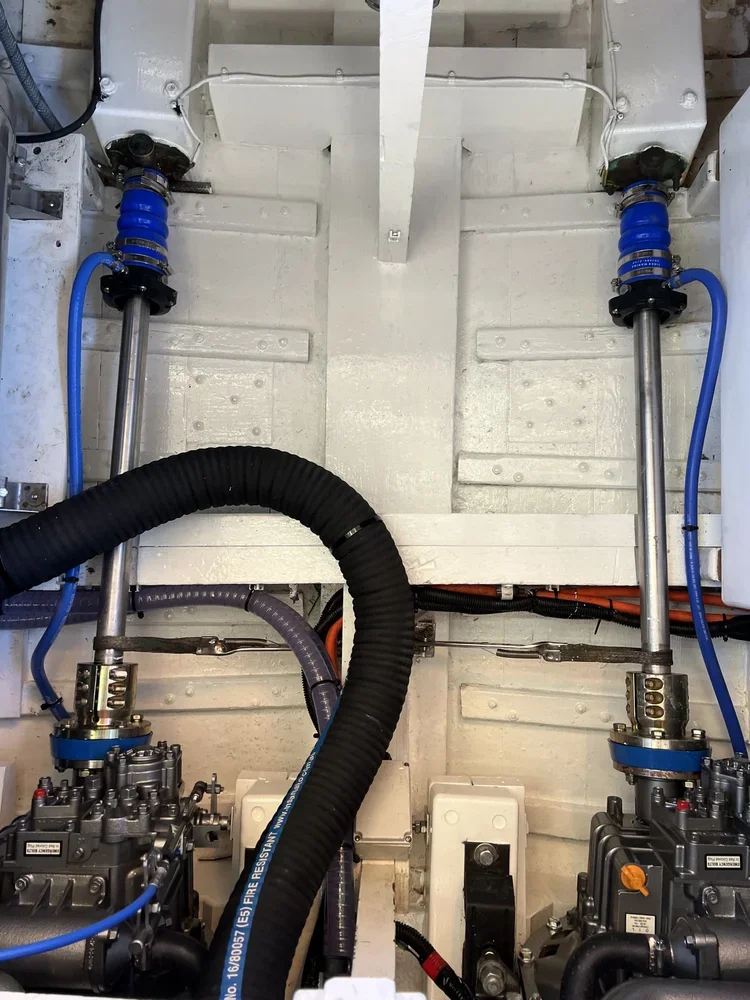 Mechanical or engineering equipment with hydraulic or pneumatic cylinders, hoses, and pipes mounted on a white metal surface.