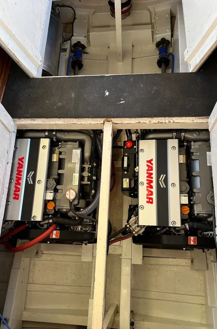 Two boat engines with Yanmar branding installed in a boat, with visible plumbing and wiring.